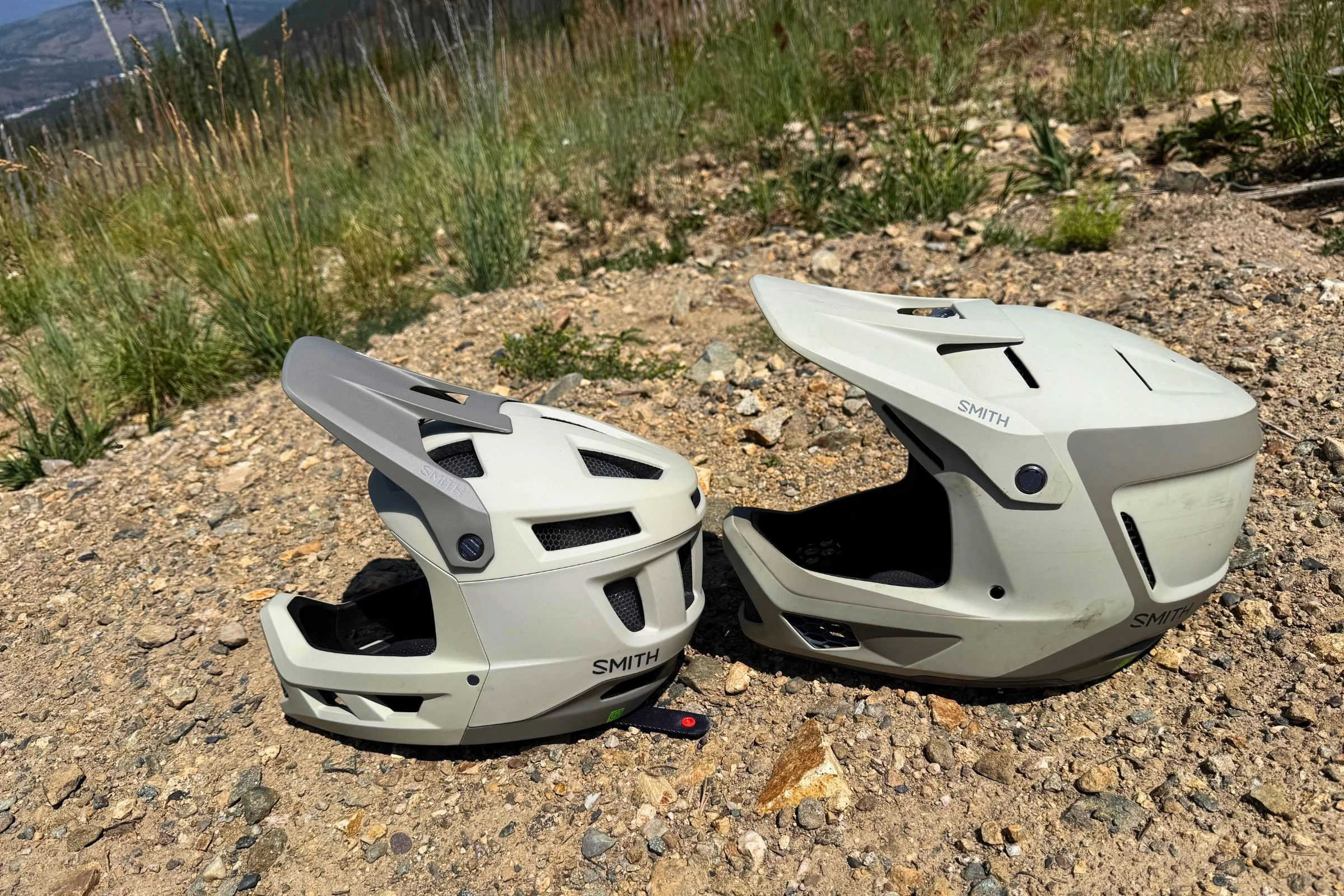 A Smith Hardline and Smith Mainline helmet positioned side by side on a mountain ridge.