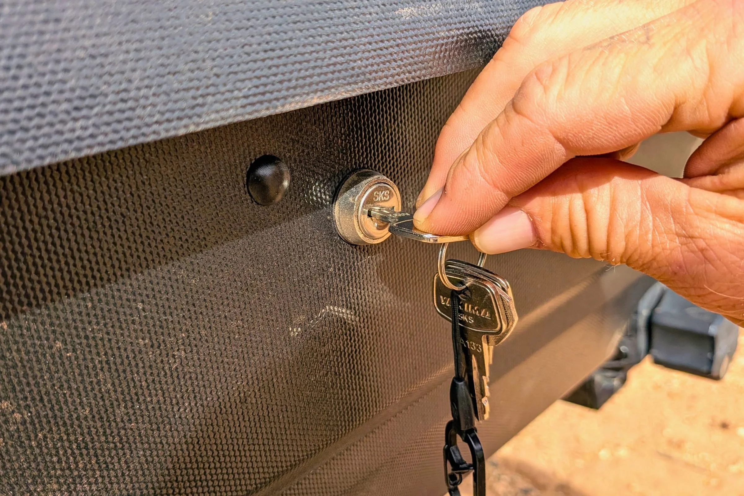 Hand inserting a key into the lock on a Yakima EXO GearLocker.