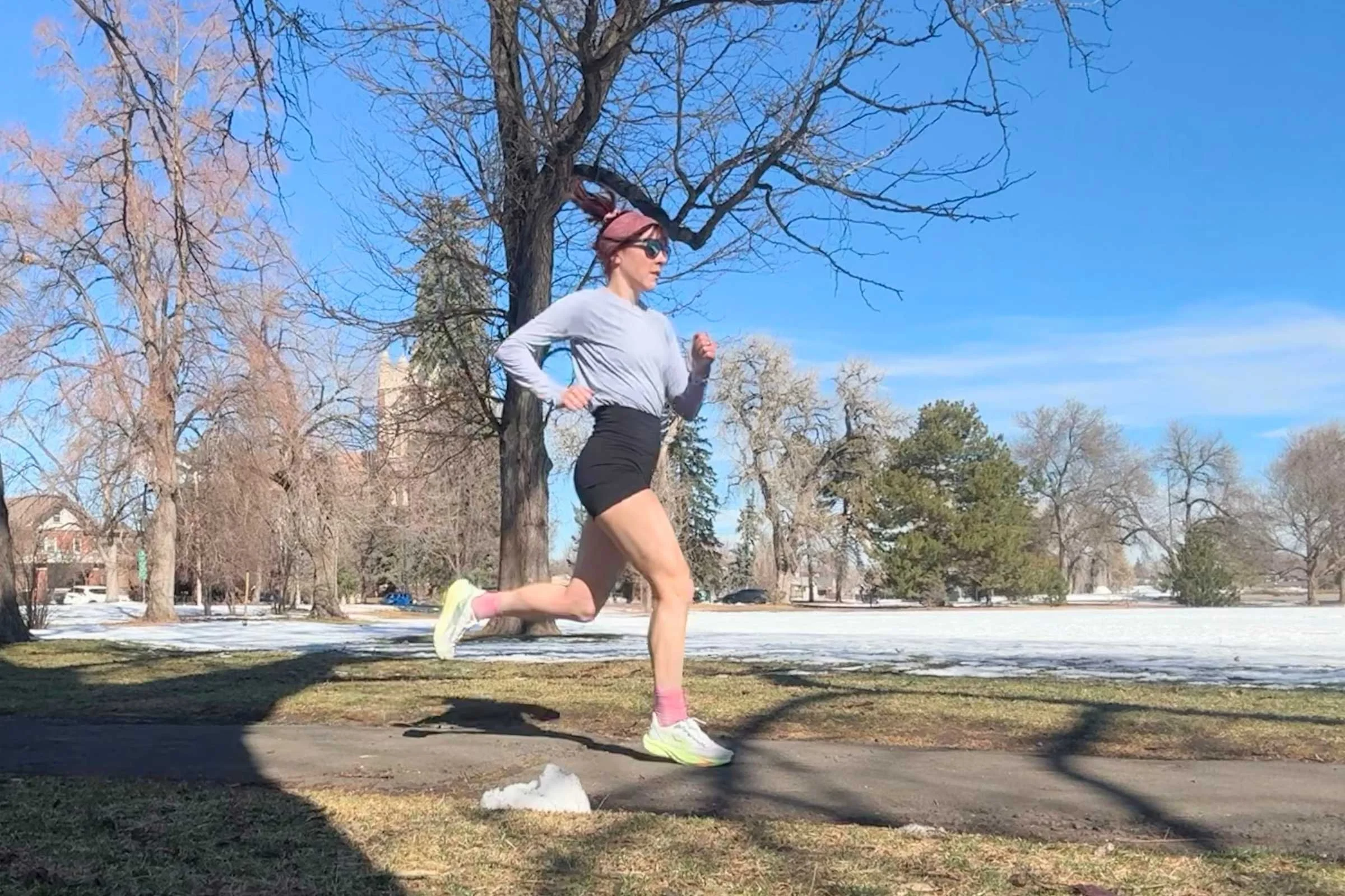 Woman running on a park path wearing REI Co-op Swiftland Grid Running Shirt.
