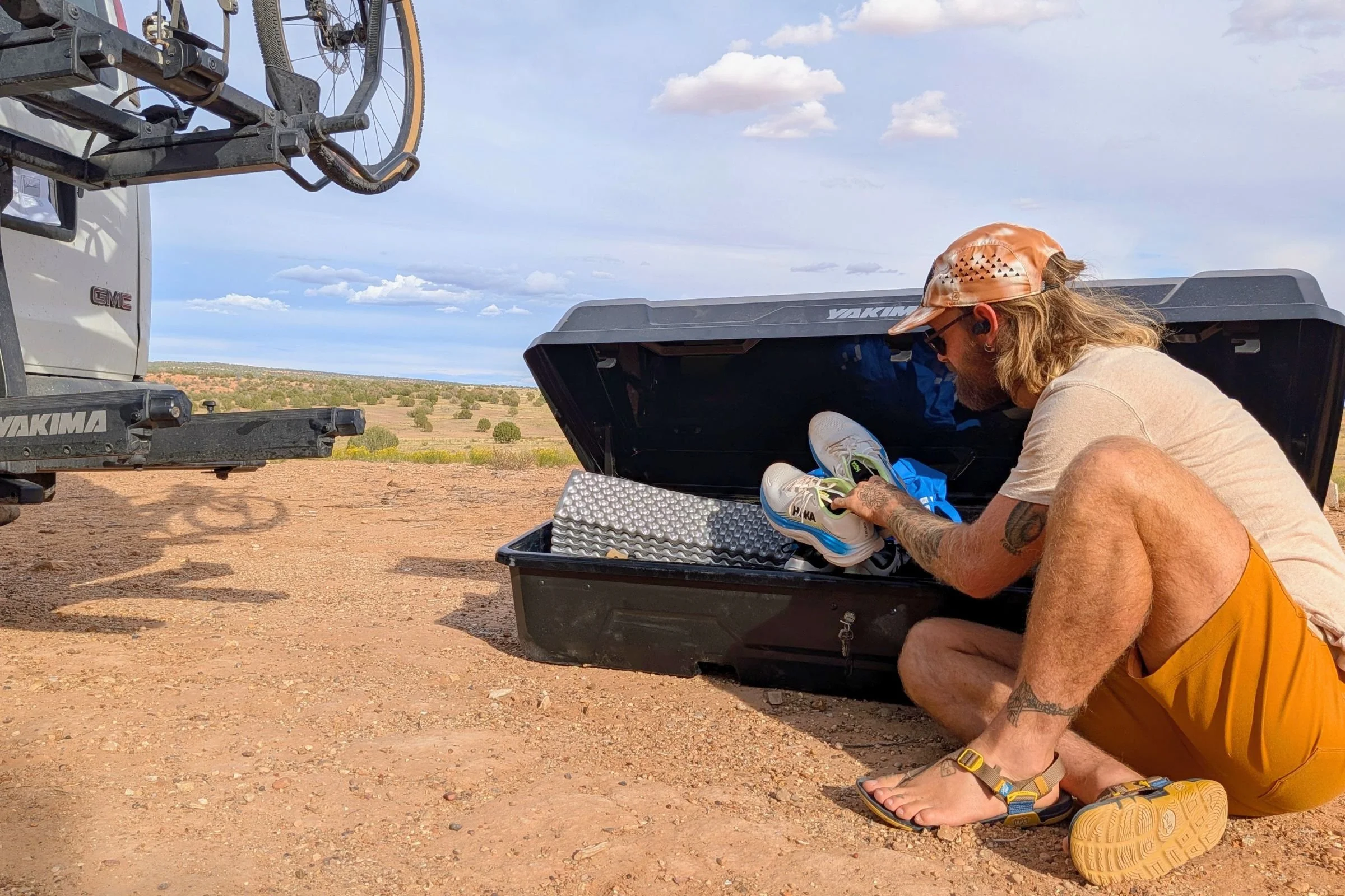 Tester sorting gear inside a Yakima EXO GearLocker on the ground beside a van.