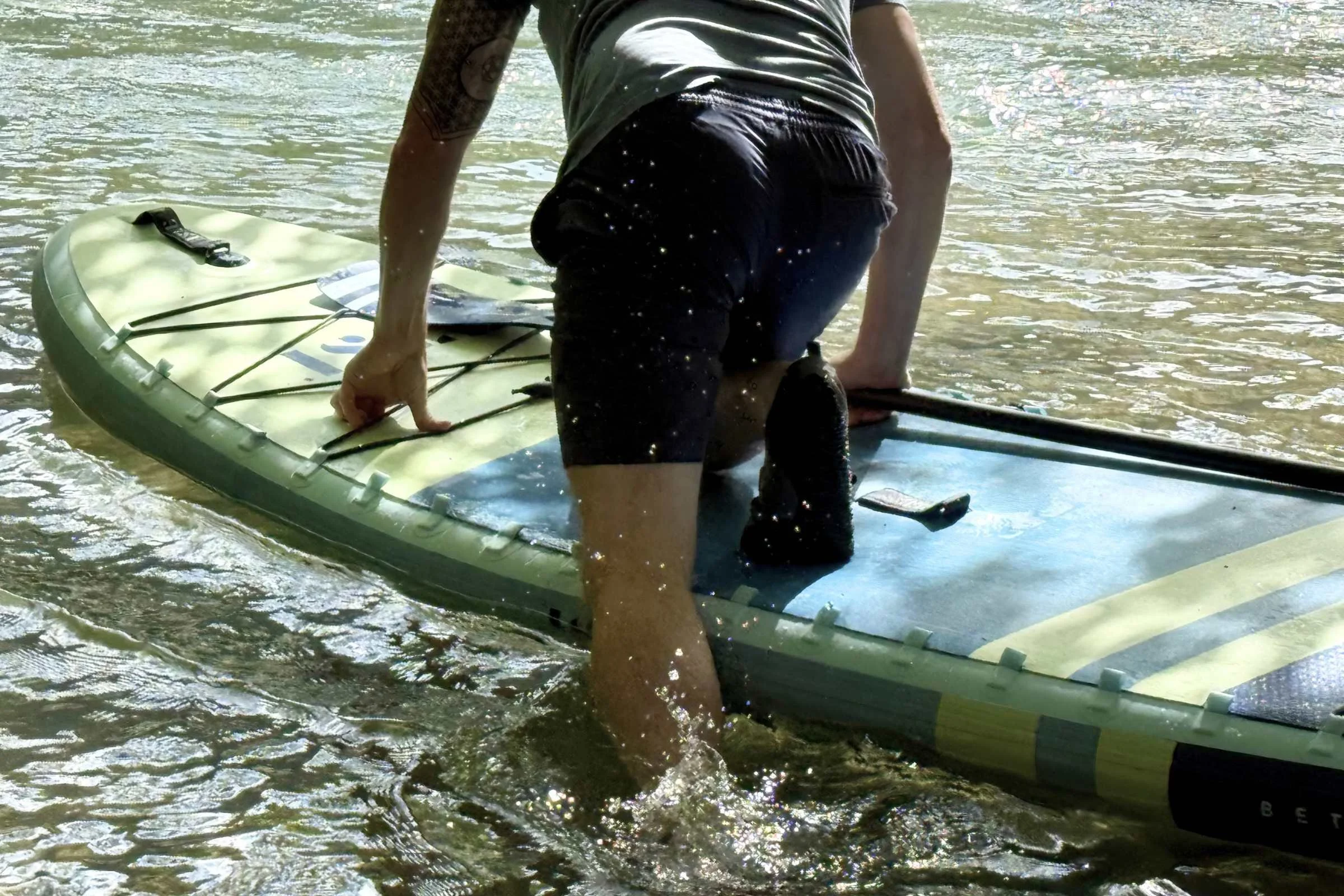 Testing a pair of water shoes while getting on a SUP from shallow water