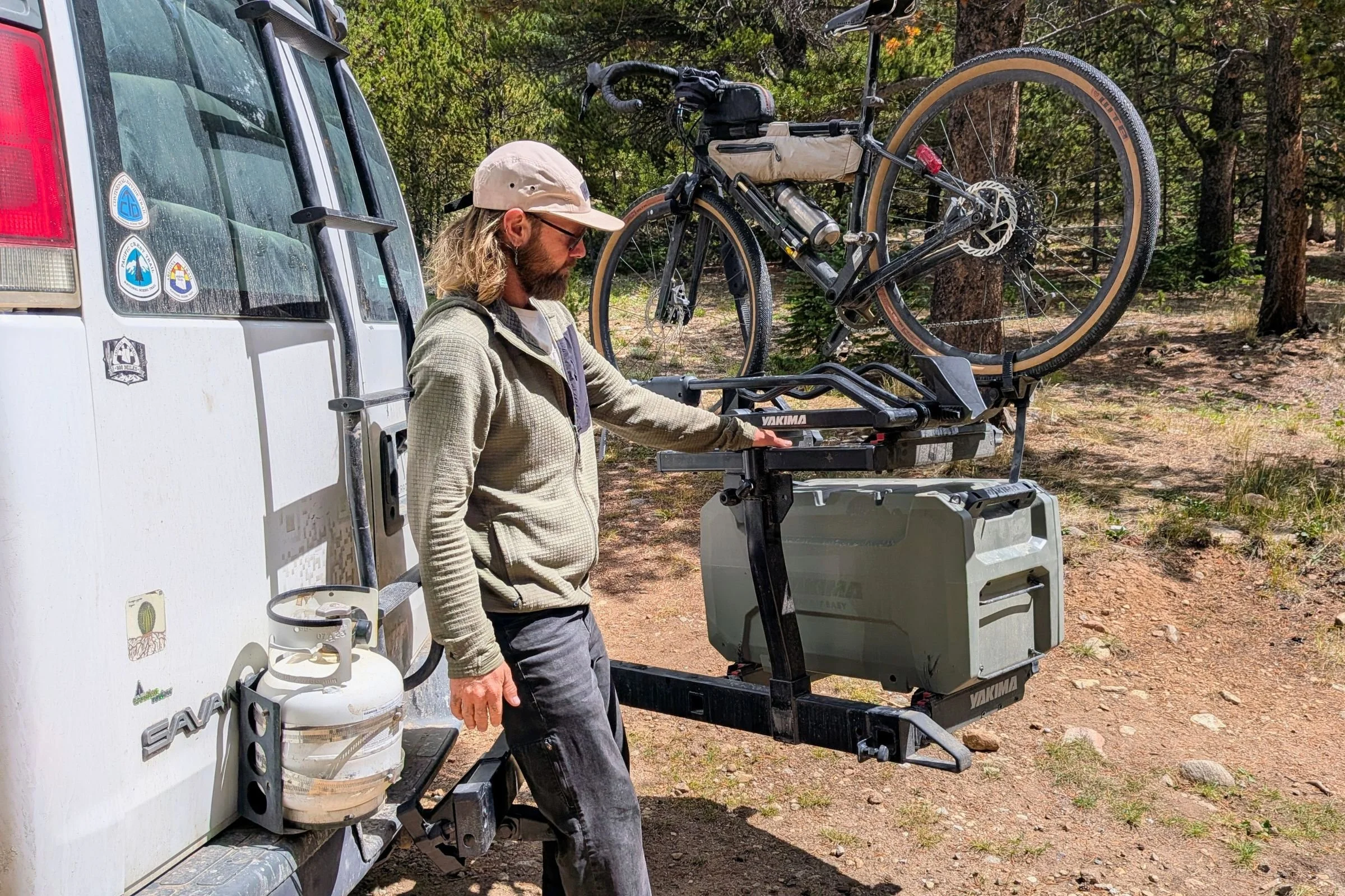 A man loads a bicycle onto a Yakima EXO Swing attached to a van.