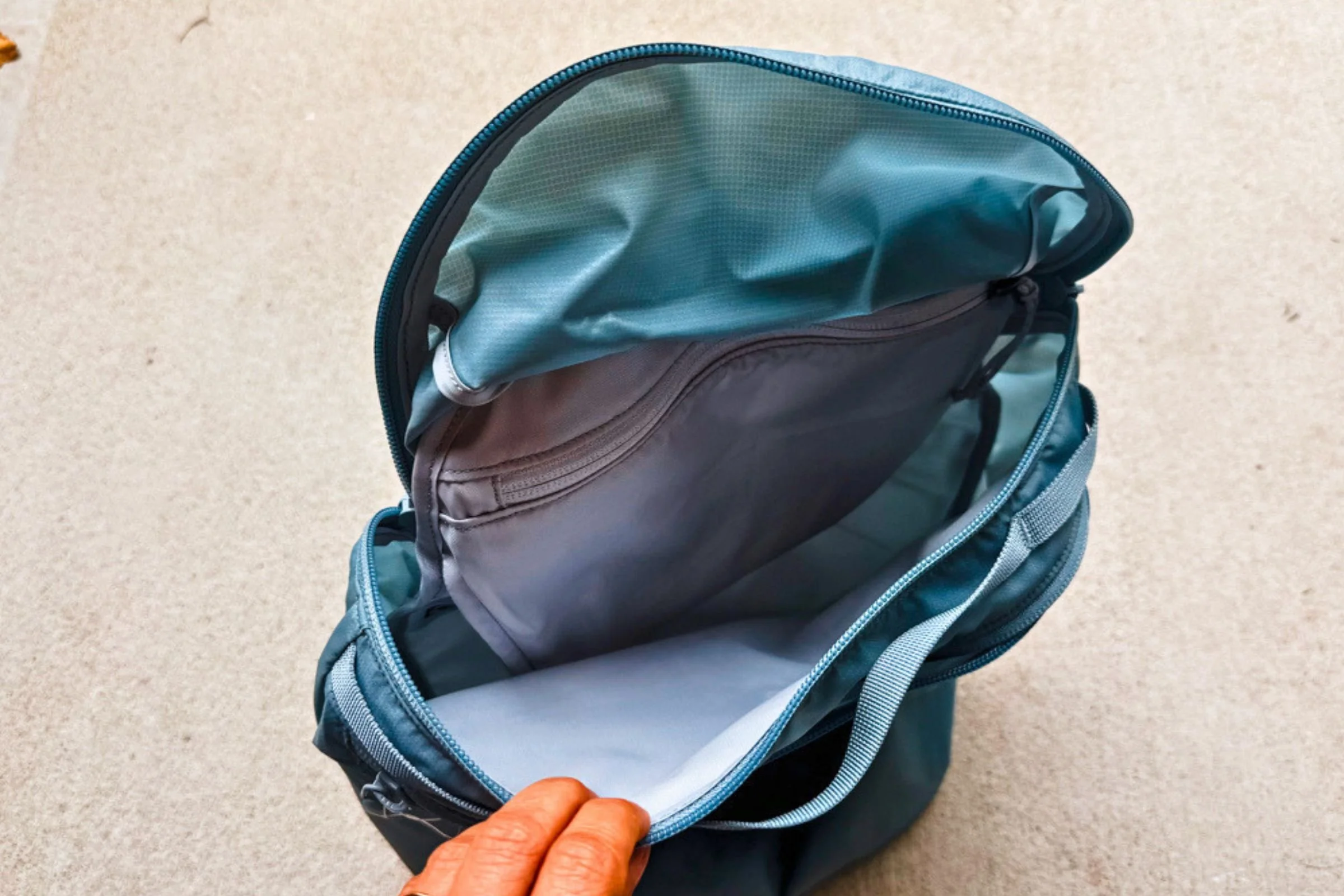 Open Arc’teryx Heliad 15 backpack showing its internal sleeve and zippered pocket.