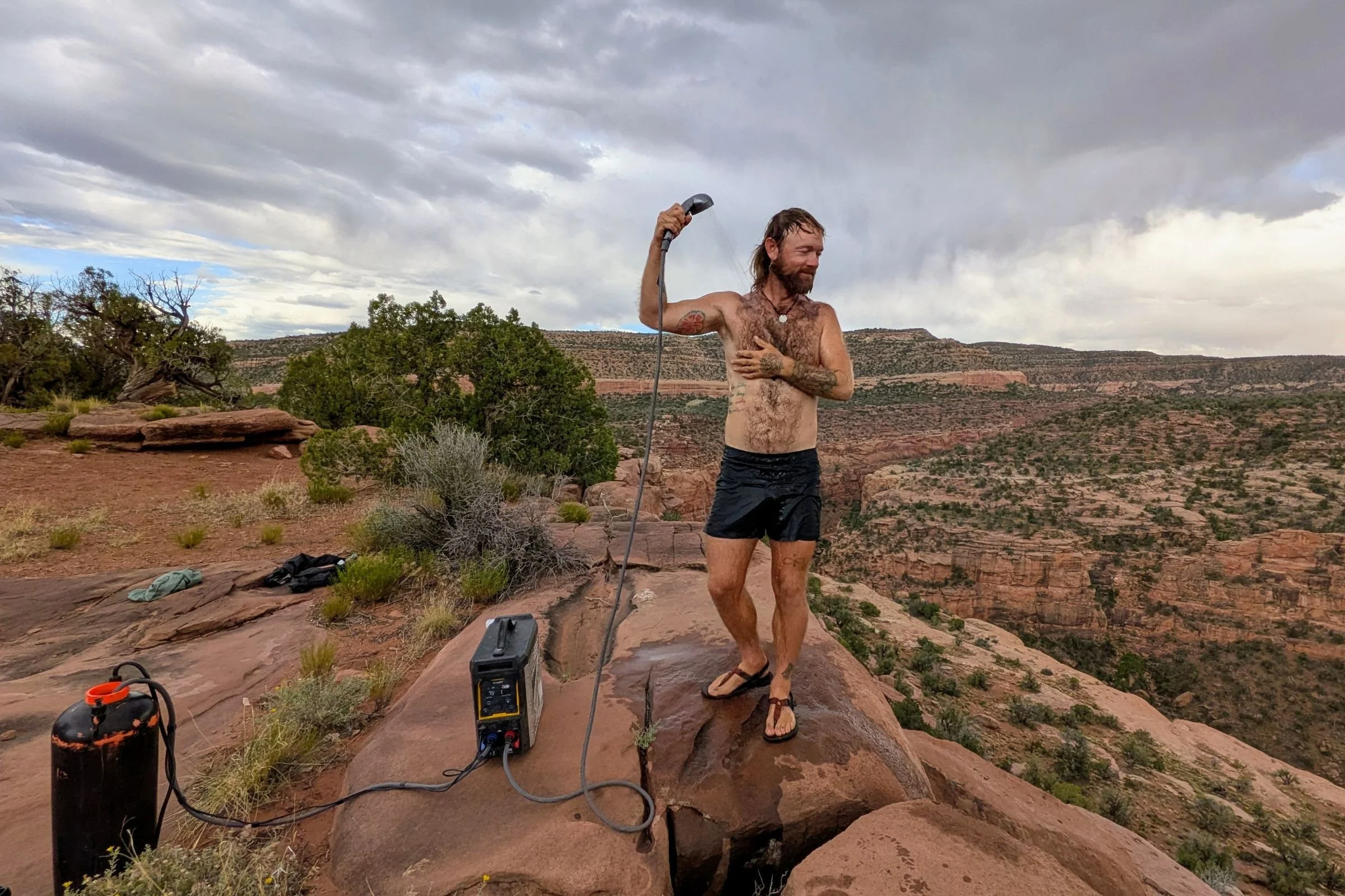 Man taking a shower with the handheld shower wand of the BougeRV water heater.