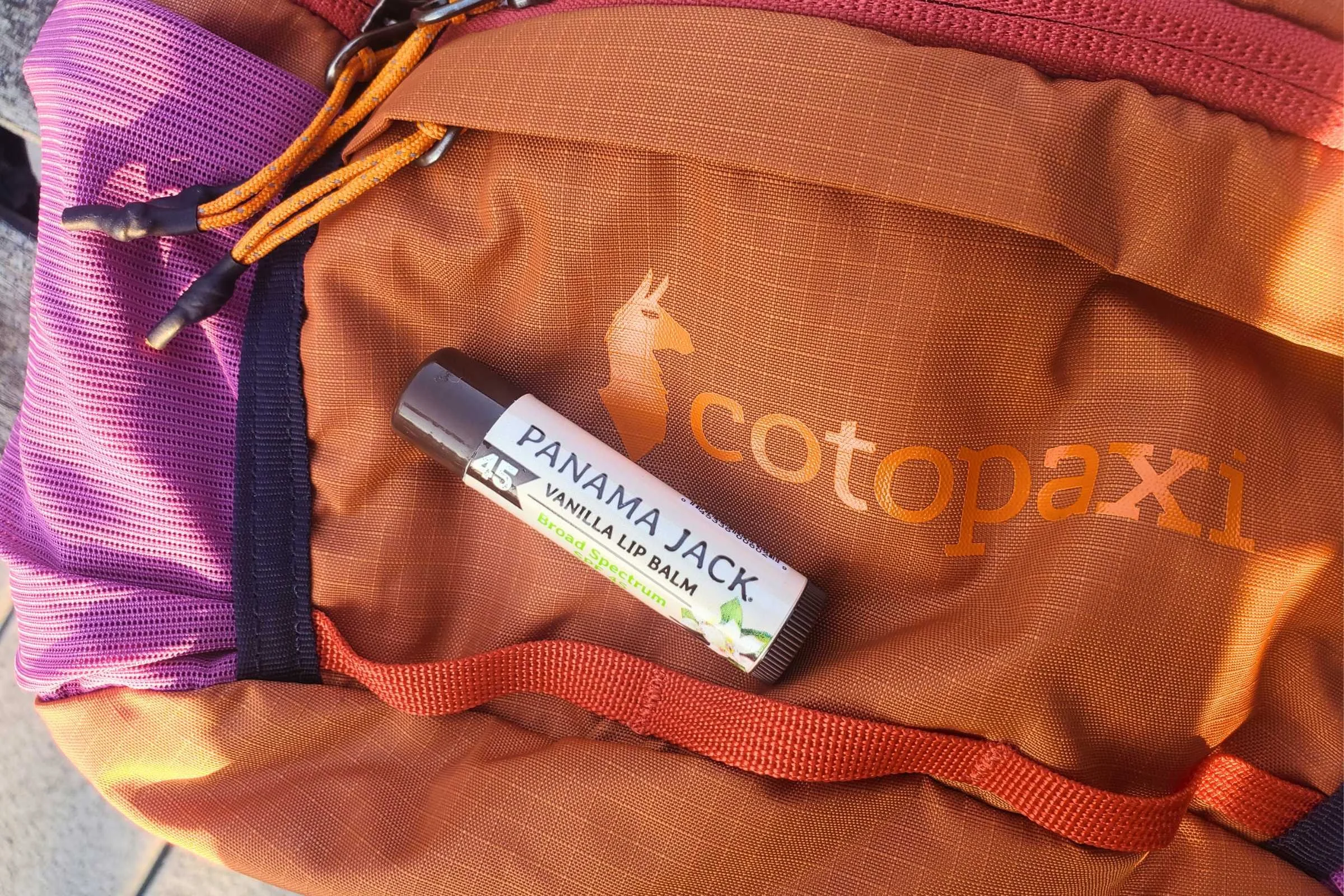 Panama Jack Sunscreen Lip Balm SPF 45 resting on Cotopaxi fanny pack during outdoor hiking and travel testing
