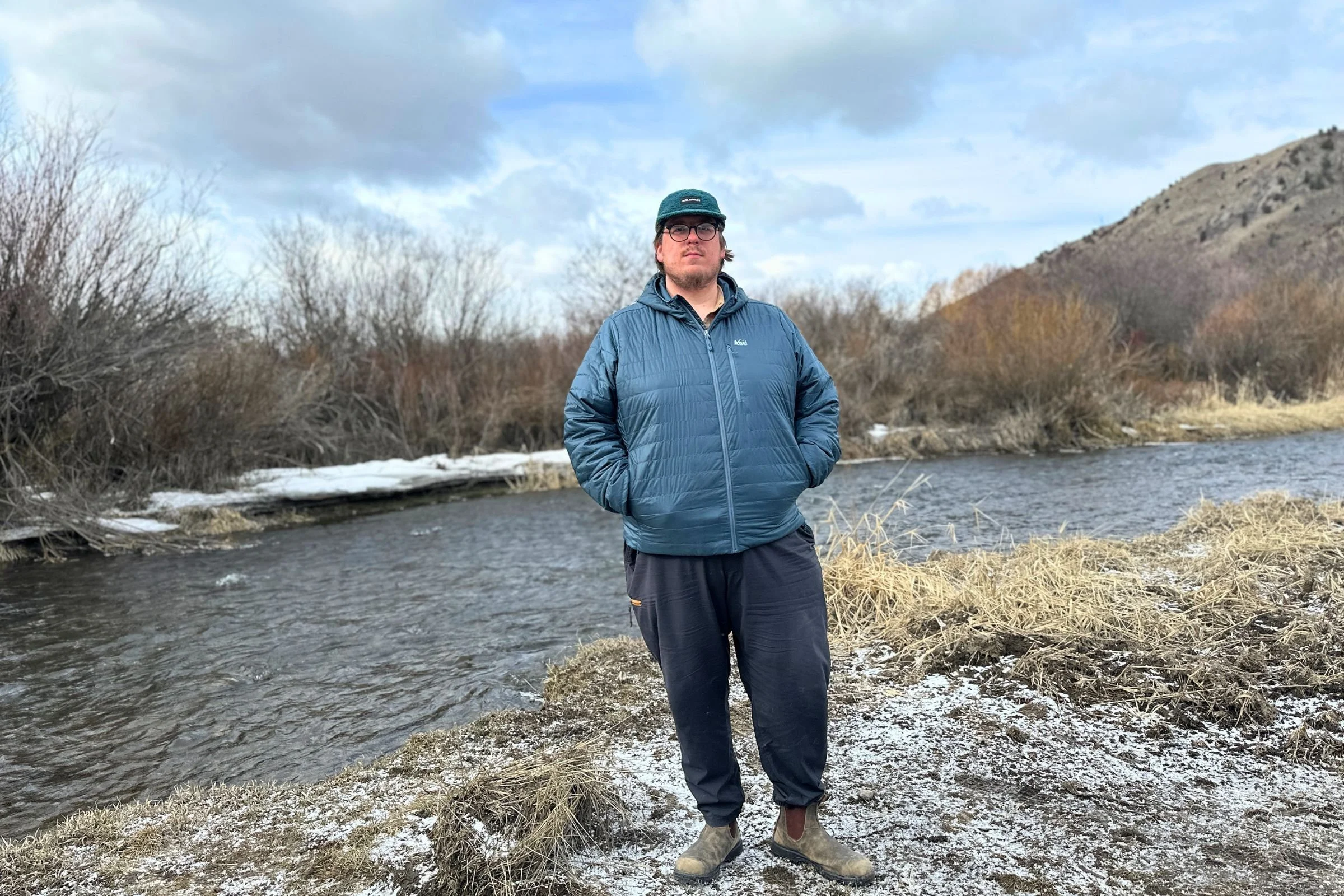 Hanging out by a stream on a snowy day in the REI Microtrek Insulated Hoodie