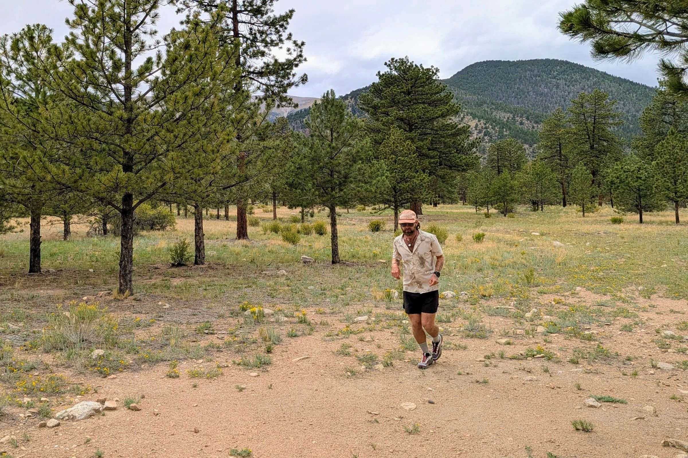 A man wearing Salomon Genesis 2 Trail Running Shoes stands in an open field.
