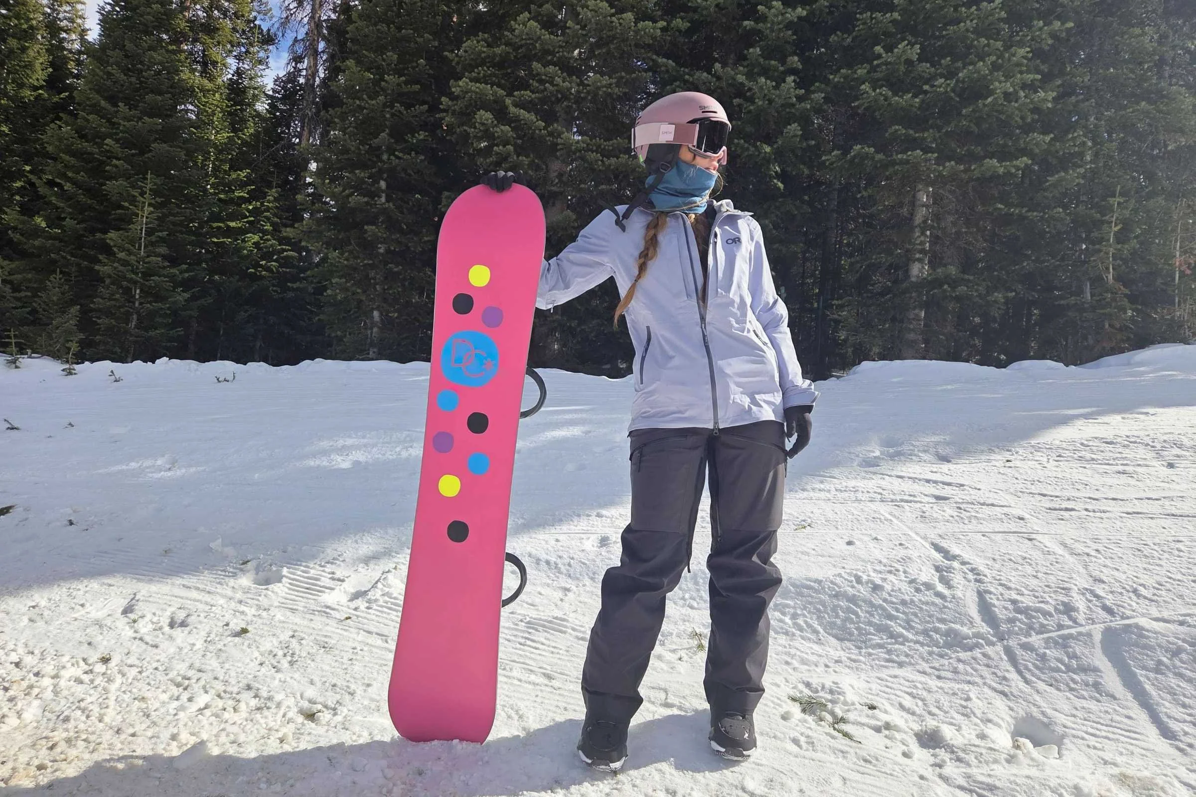 Snowboarder holding a pink snowboard and wearing the Outdoor Research Carbide Jacket
