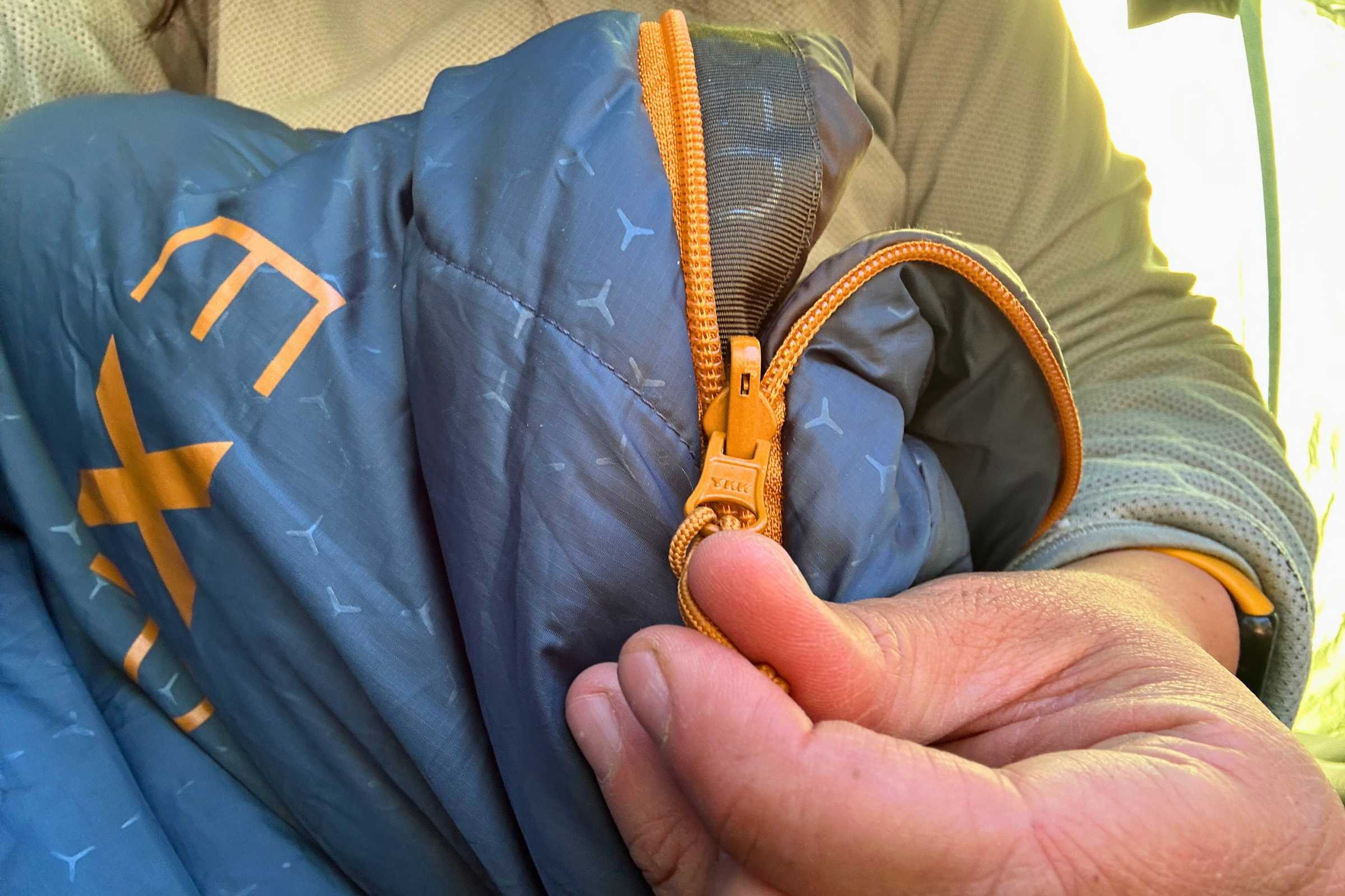 orange zipper being pulled on a blue exped deepsleep sleeping bag
