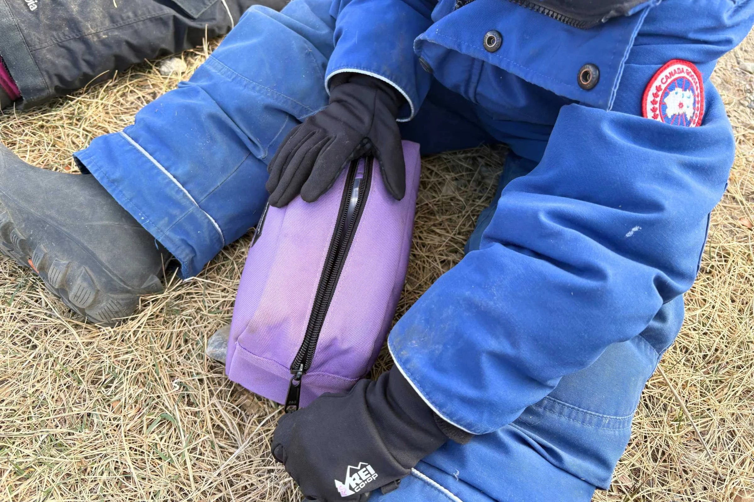 Child wearing REI Flash Gloves while opening gear pouch outdoors