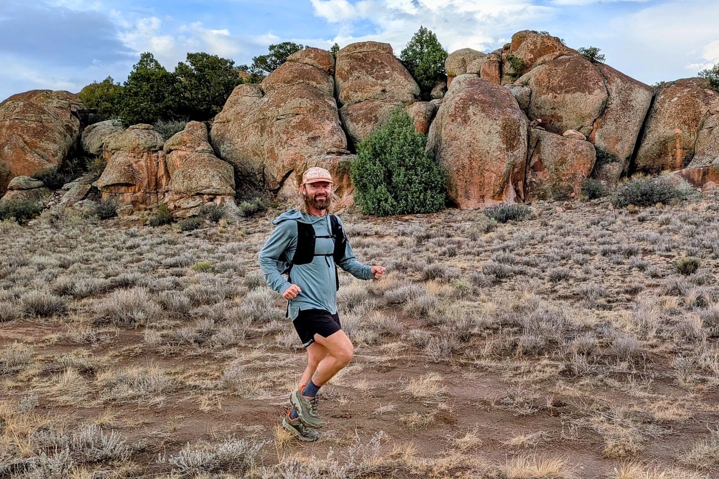 A man wearing the Altra Olympus 7 runs through a rocky desert landscape.