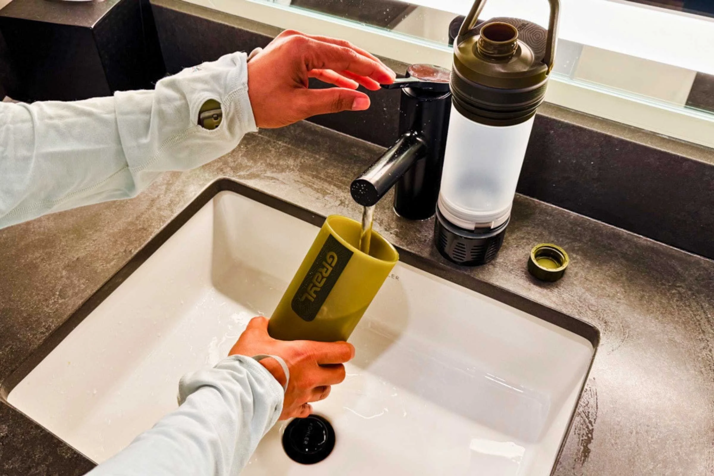 A filter water bottle being filled at a tap, with the filter element visible through the transparent body. Photo courtesy Karthika Gupta