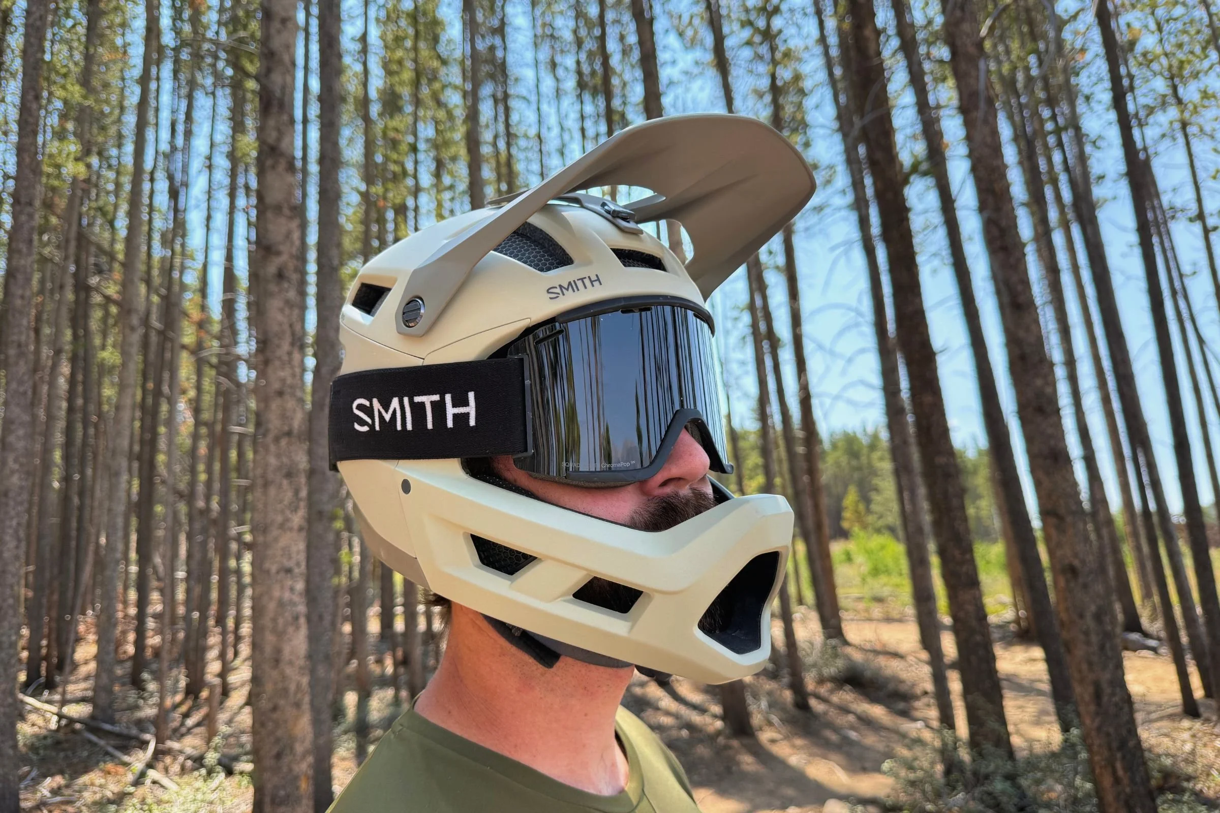 A person wearing Smith Mainline Mips goggles and Smith Mainline Mips stands among trees in the woods.
