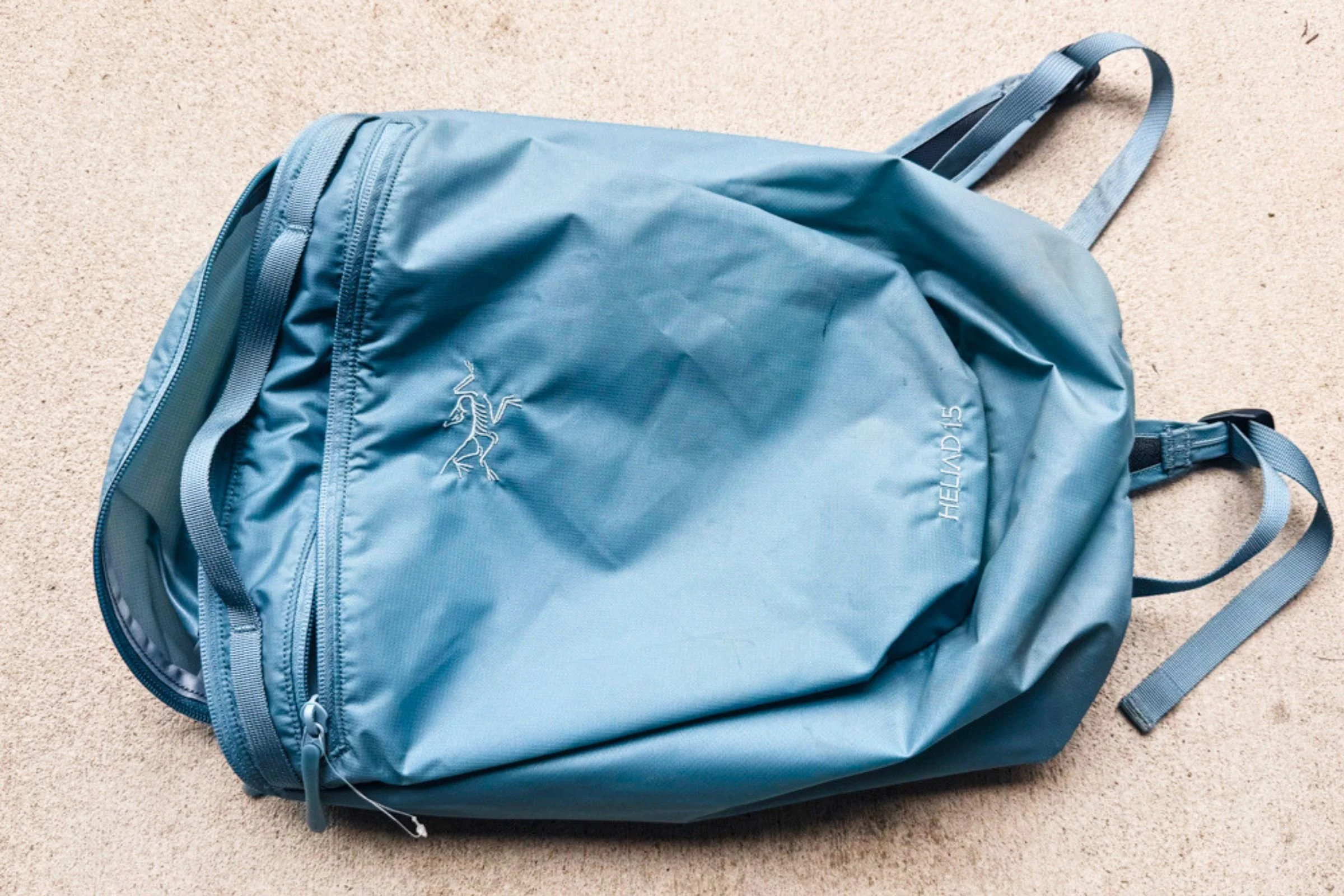 Blue Arc’teryx Heliad 15 backpack laid flat with its front pocket facing upward.