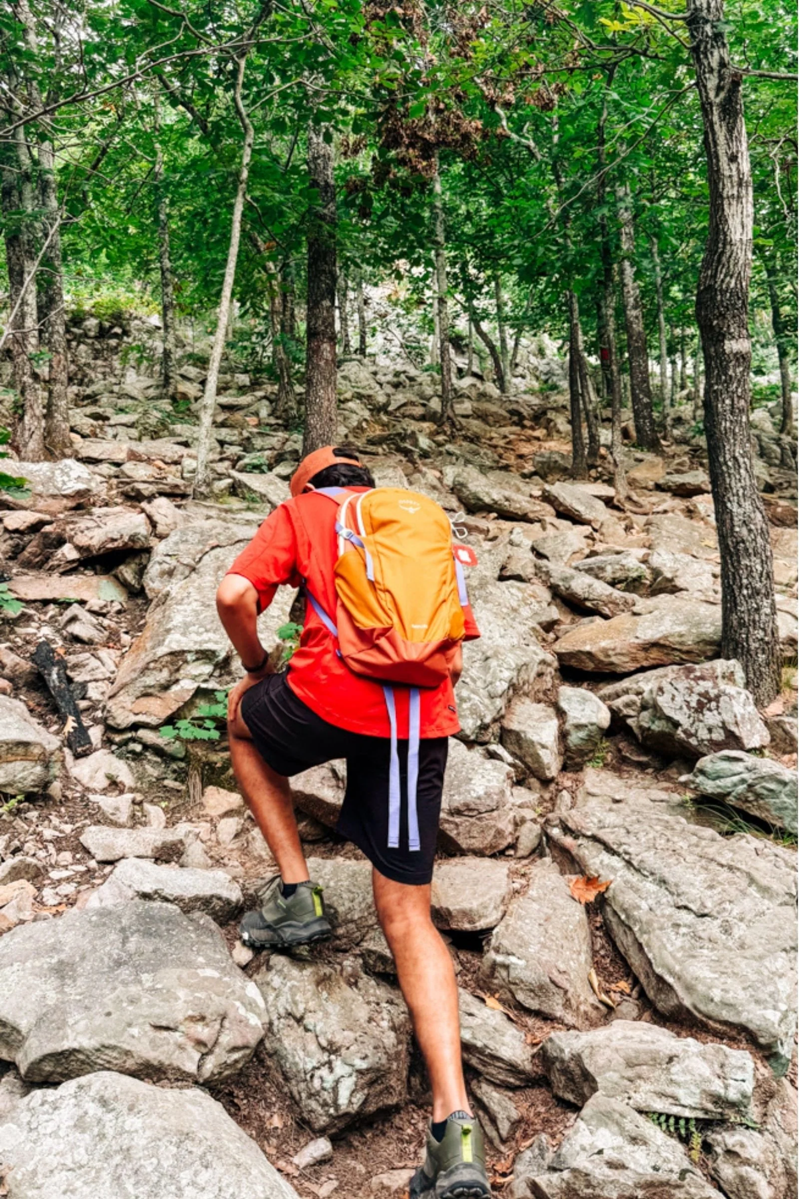 A person wearing the Osprey Daylite backpack while hiking up a rocky trail.