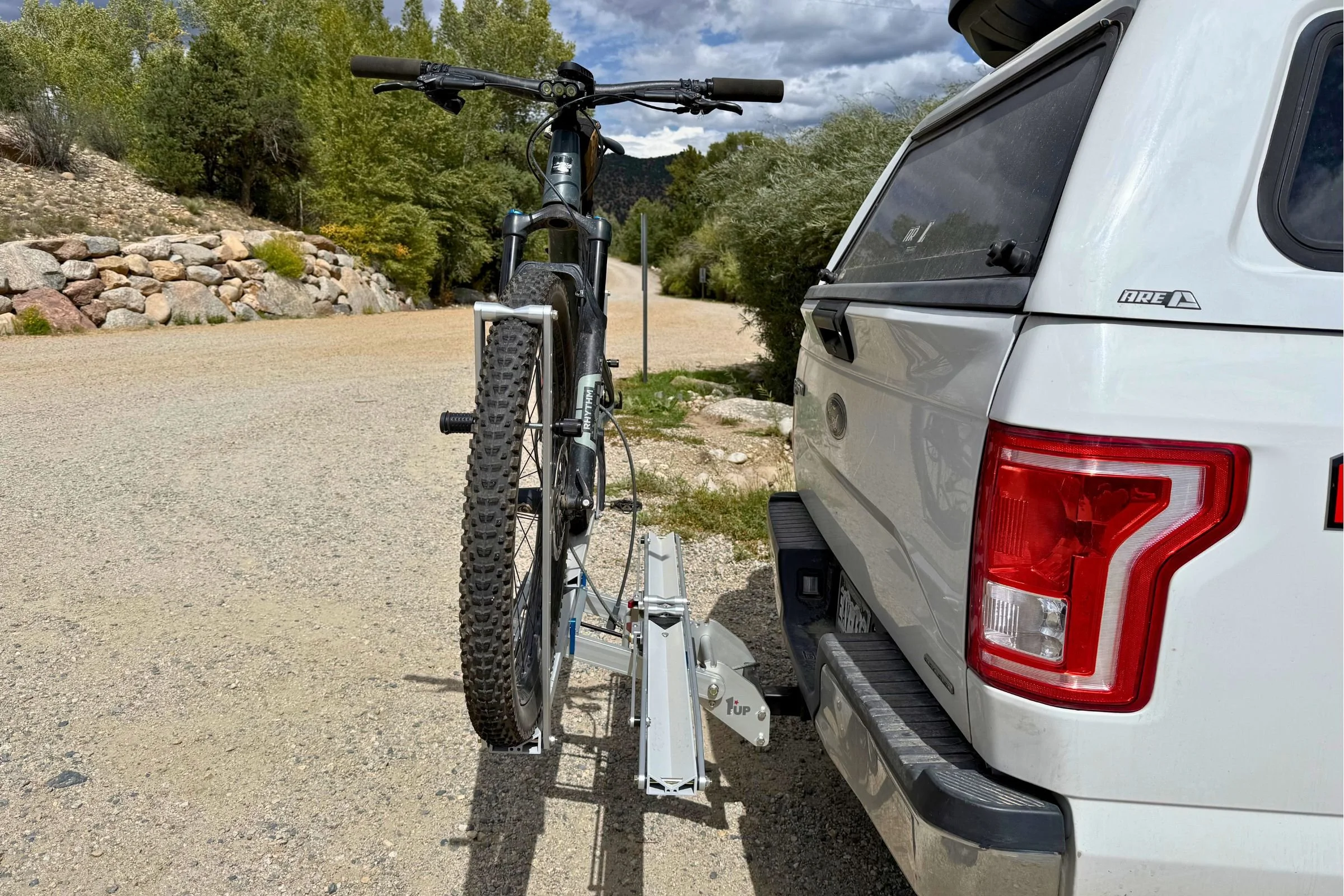 Bicycle mounted on the 1UP USA Heavy Duty Hitch Bike Rack at the back of a truck, showing tiered bike spacing.