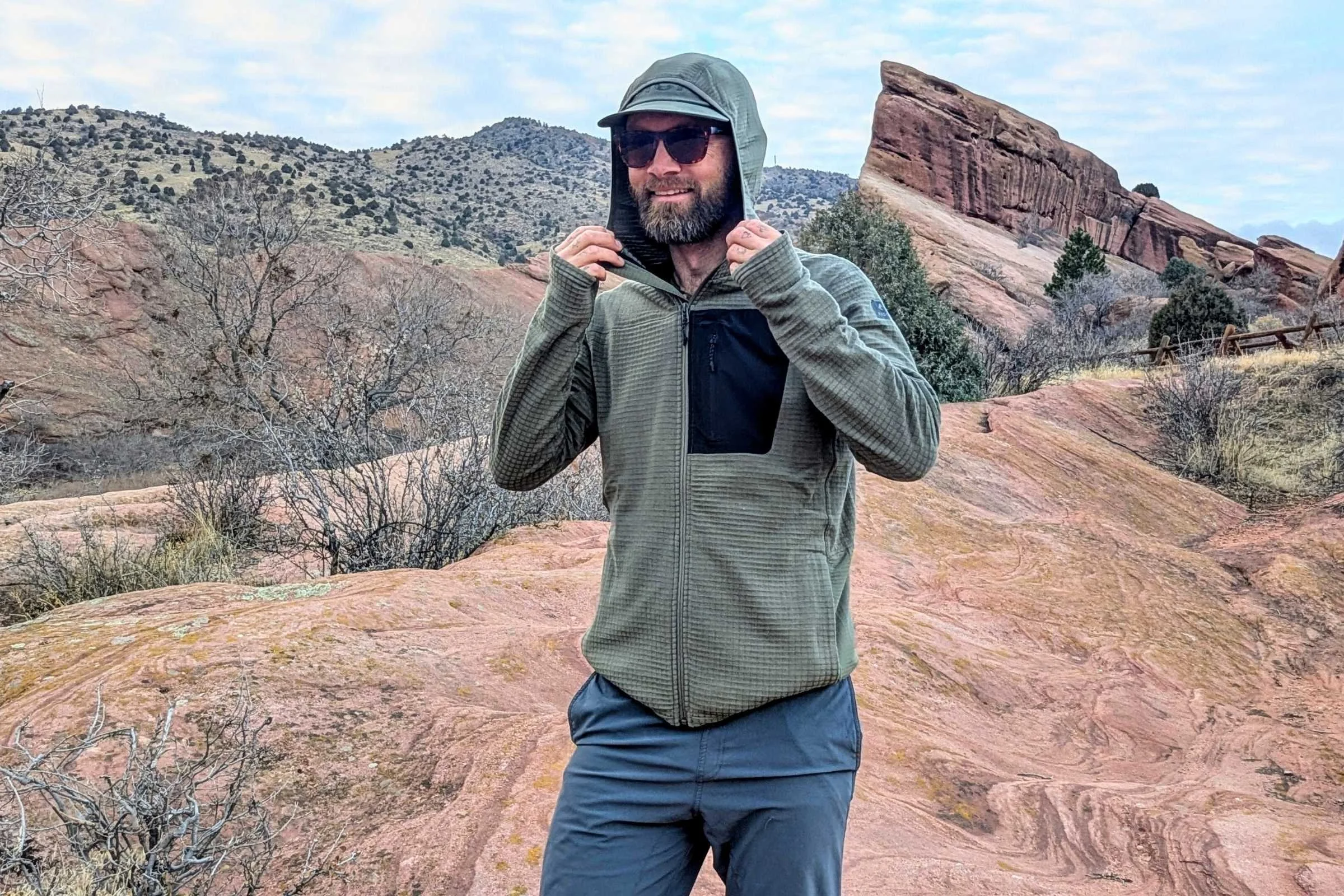 man hiking and wearing green Ridge Merino Cloudripper fleece jacket