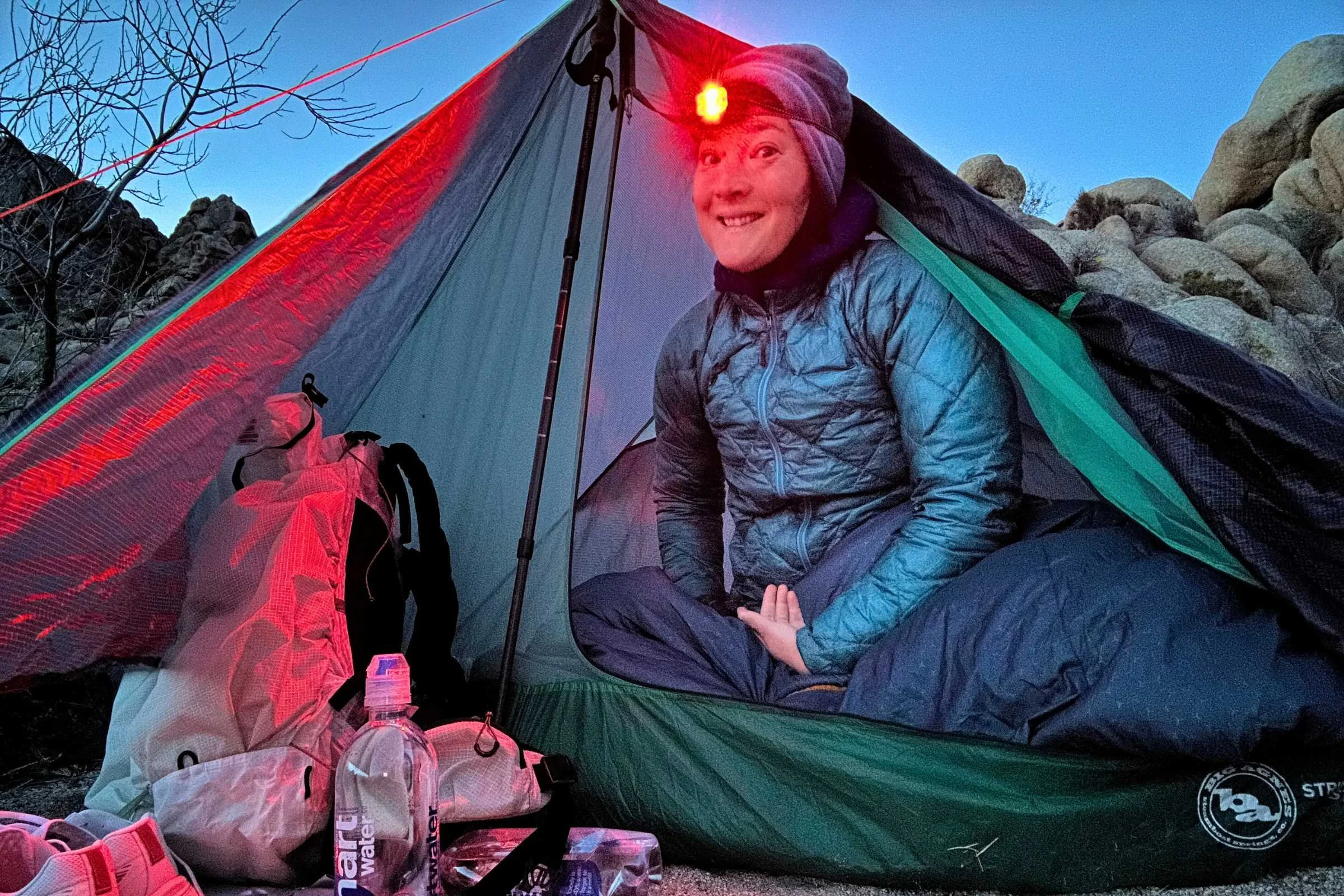 Person sitting inside Big Agnes String Ridge VST tent at dusk with headlamp