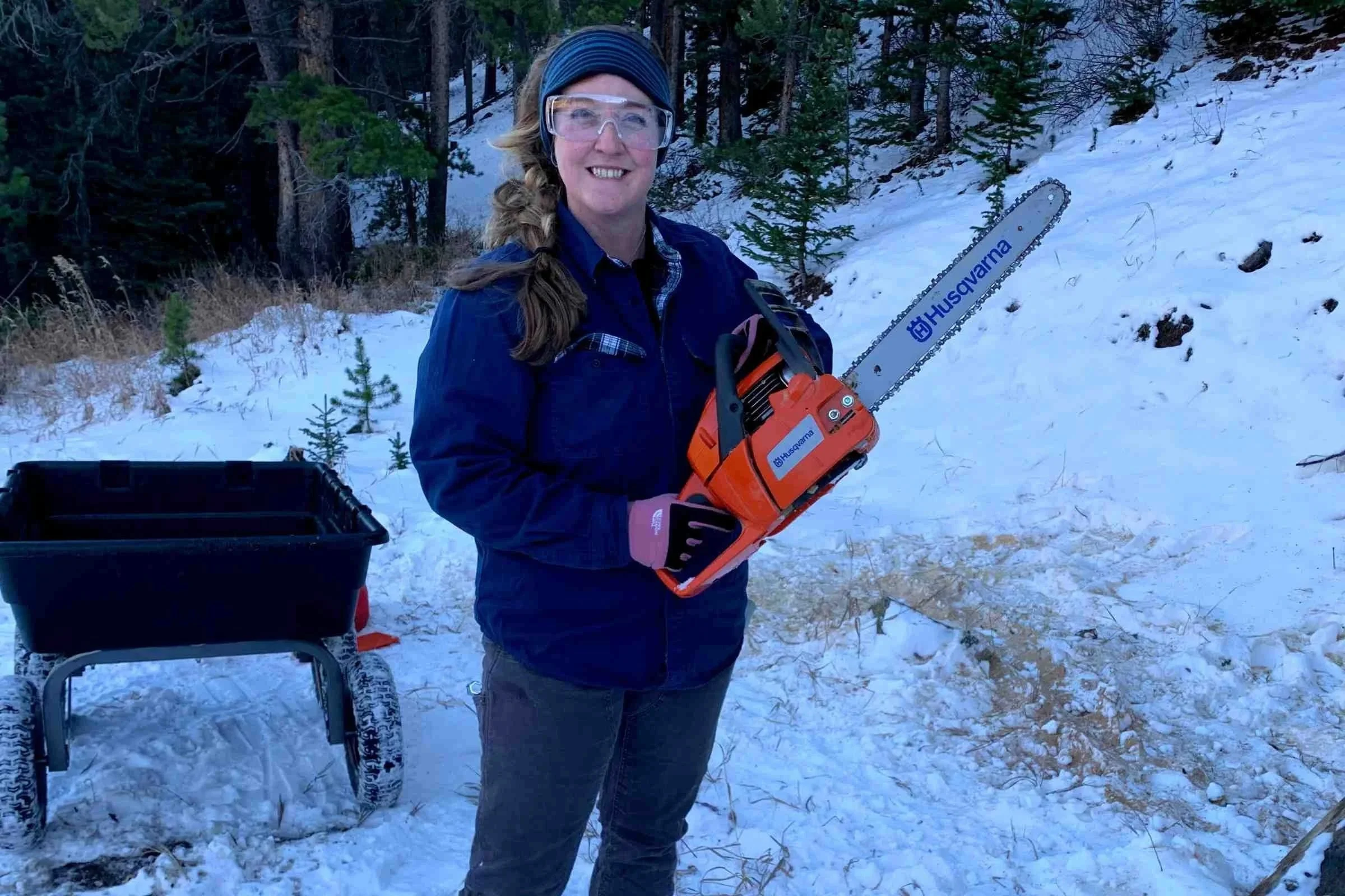 Woman wearing North Face etip gloves holding a chainsaw