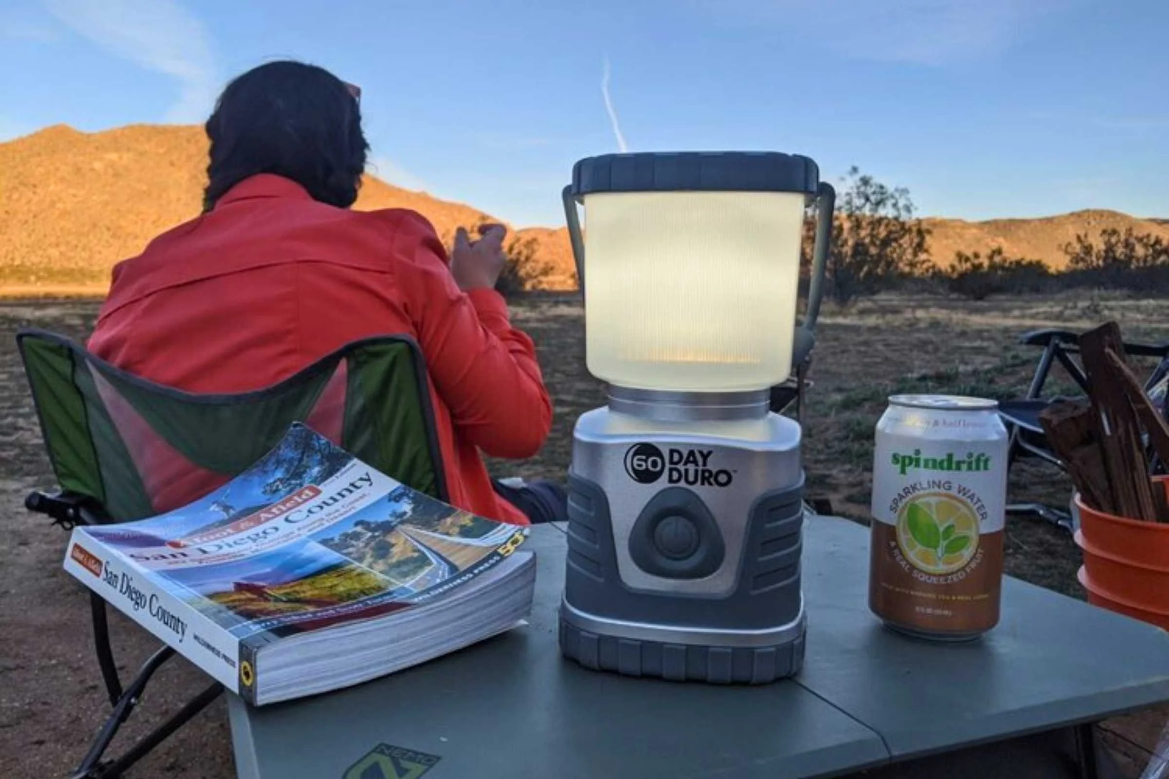 Camping lantern, guidebook, and soda on the NEMO Moonlander camp table