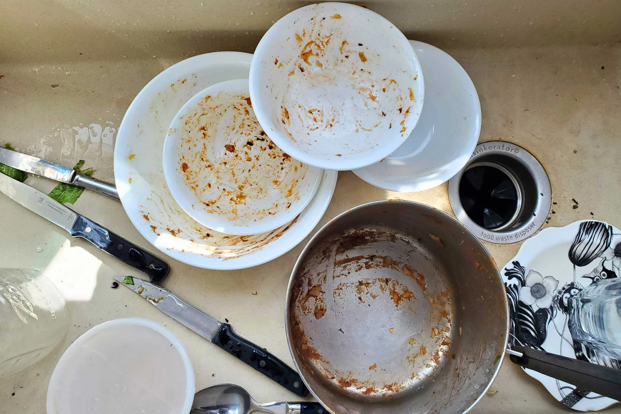 A collection of dirty bowls, plates, and pots in a kitchen sink