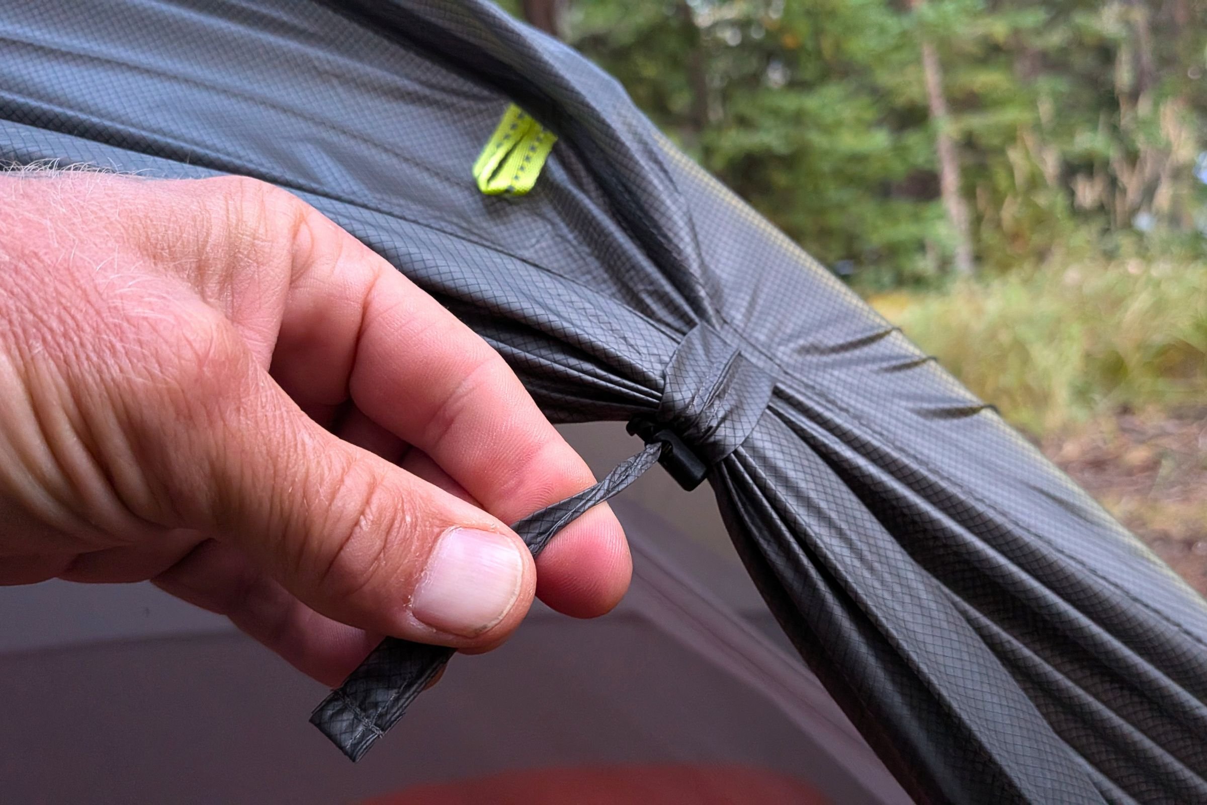 Close-up of a hand securing the rolled-back rainfly door of Gossamer Gear The Free.