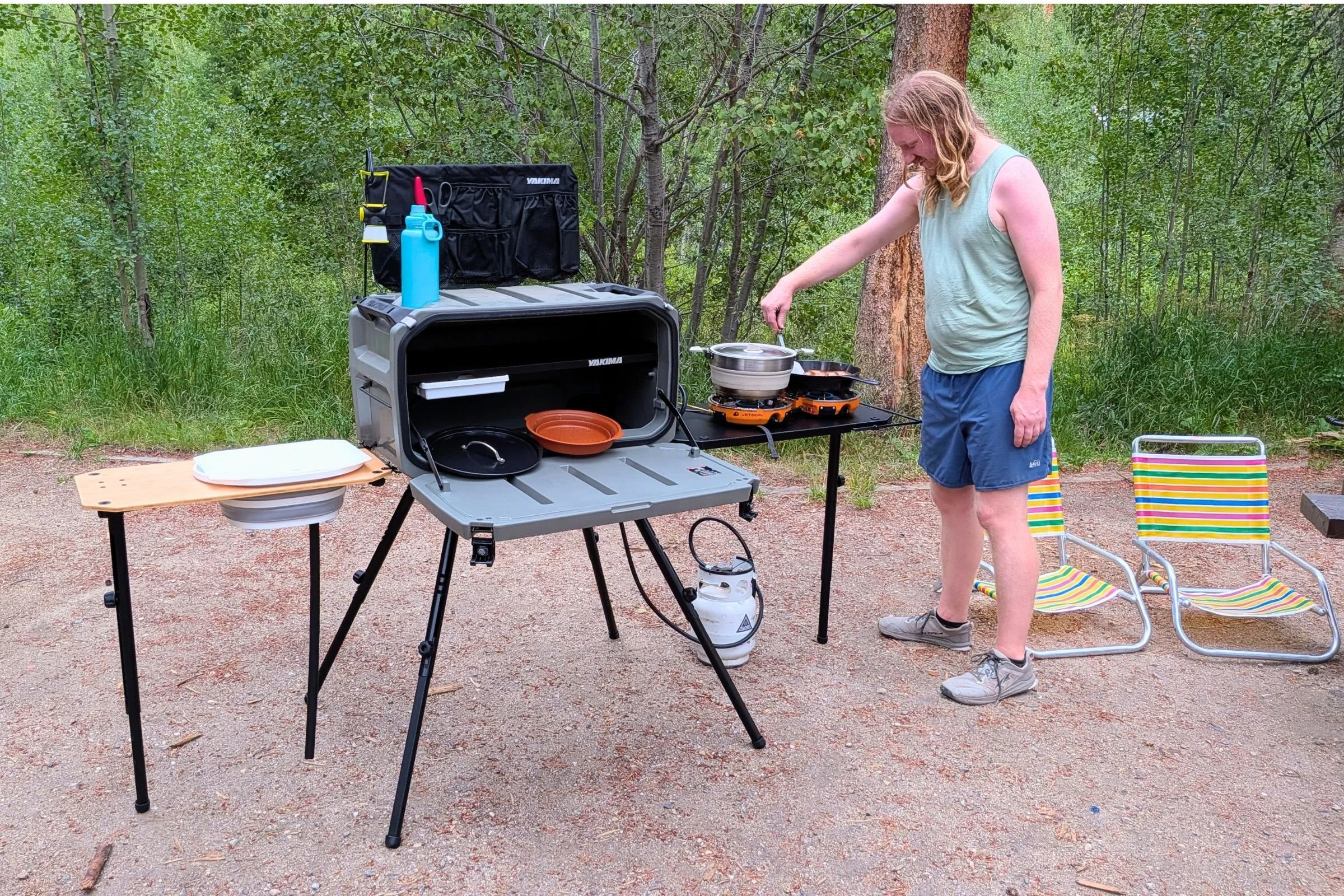 Person preparing food on a camping stove alongside the Yakima EXO OpenRange freestanding leg kit.