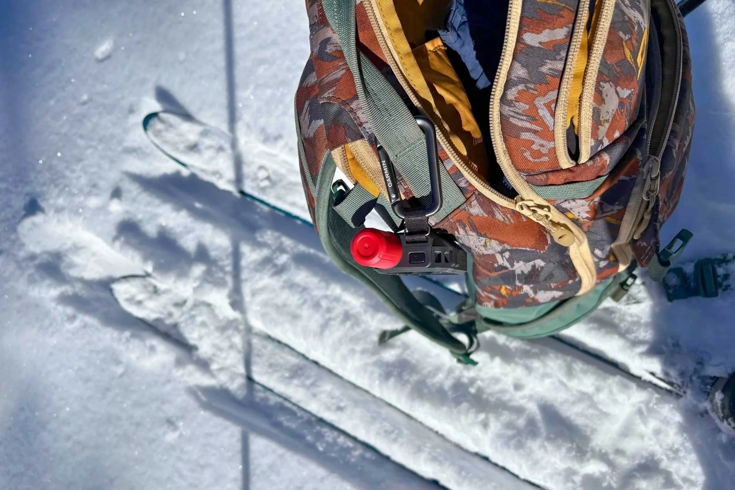 A Garmin inReach Mini 3 Plus carried outside a ski pack with the carabiner that comes with the device. The red antenna distinguishes the Plus 3 from all other Garmin GPS devices. (Dean Krakel photo, Special to Treeline Review)