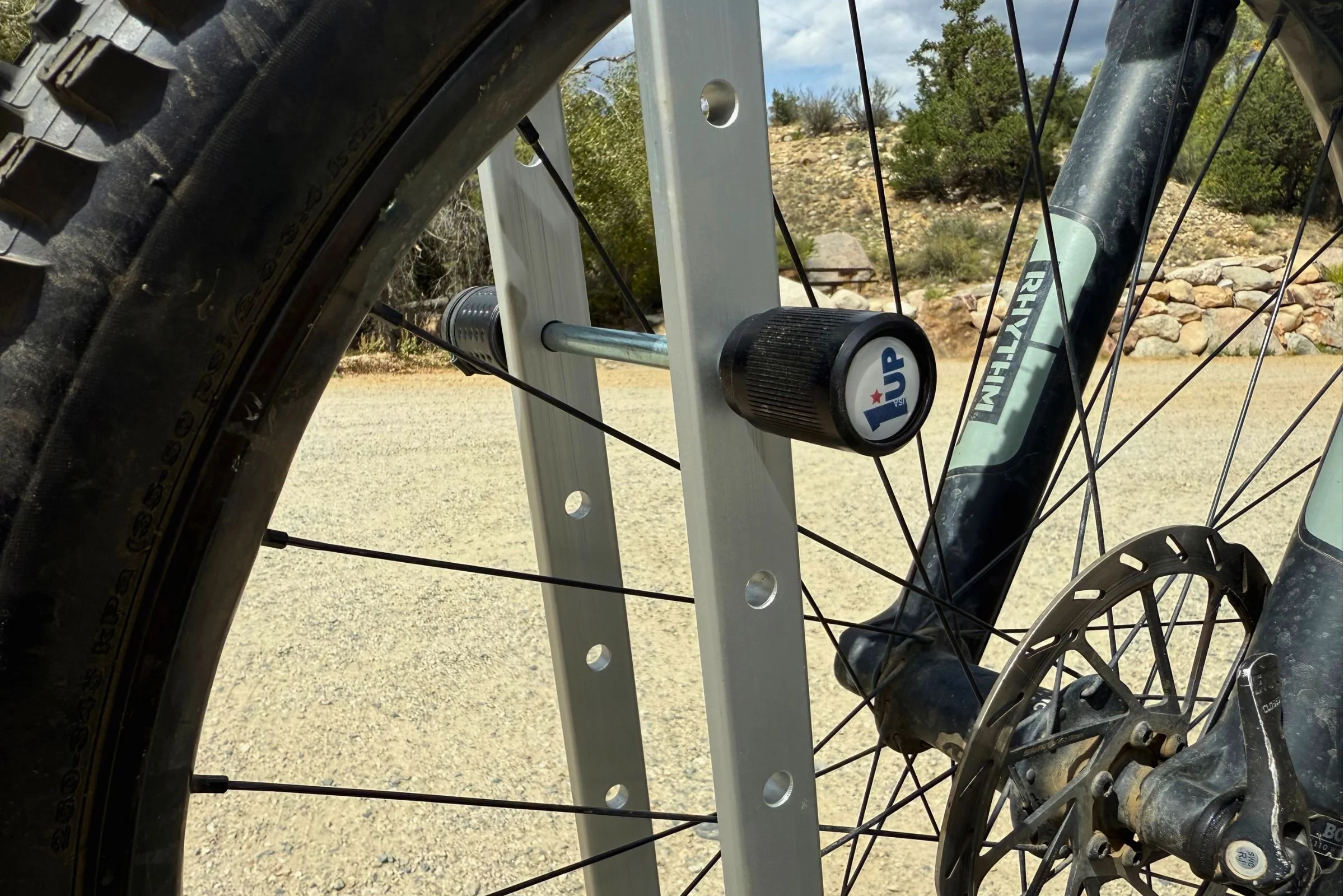 Close-up of a bicycle tire secured by the 1UP USA Heavy Duty Hitch Bike Rack, highlighting its integrated locks.