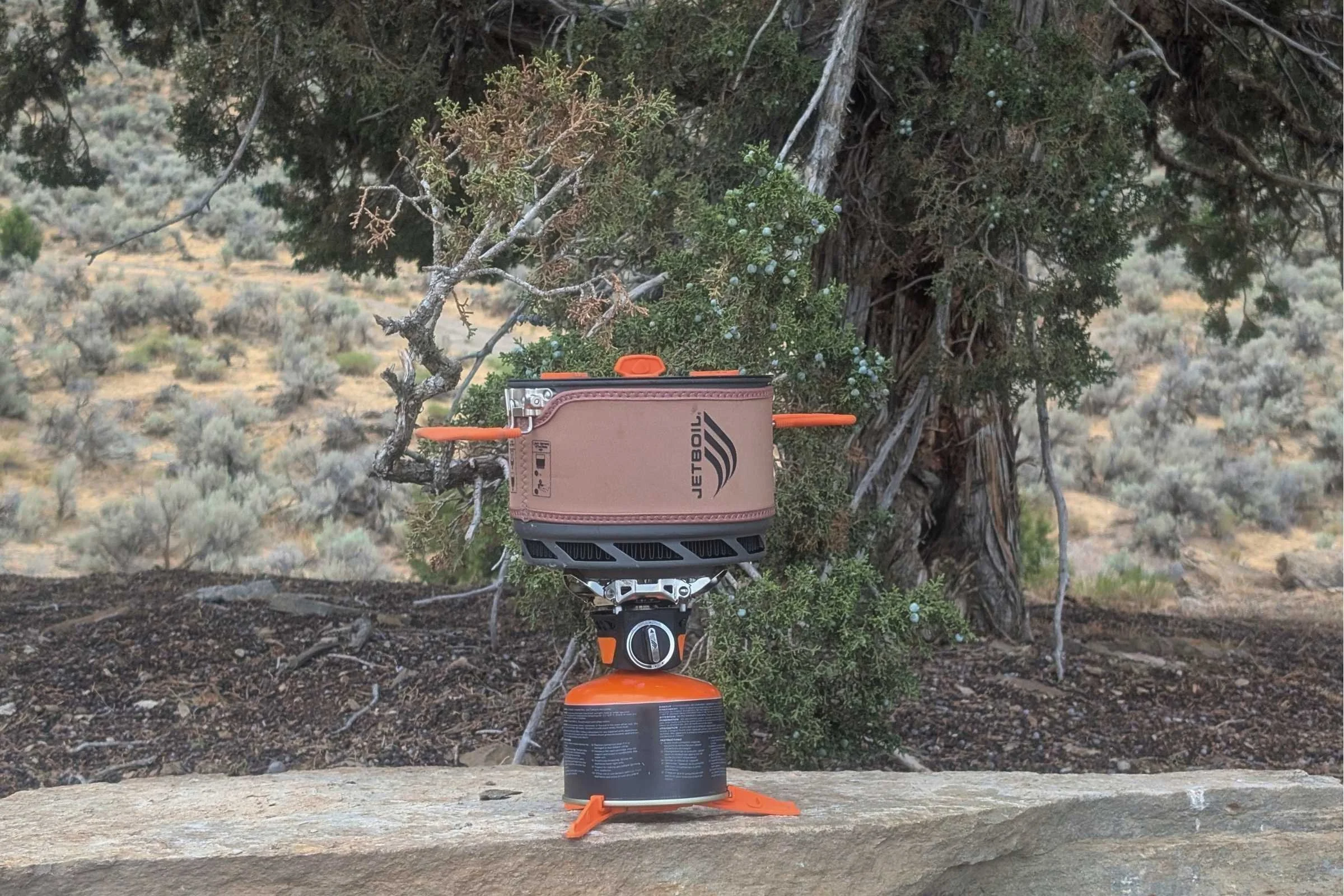 The Jetboil TrailCook set up on a rock with the pot on top of a rock.