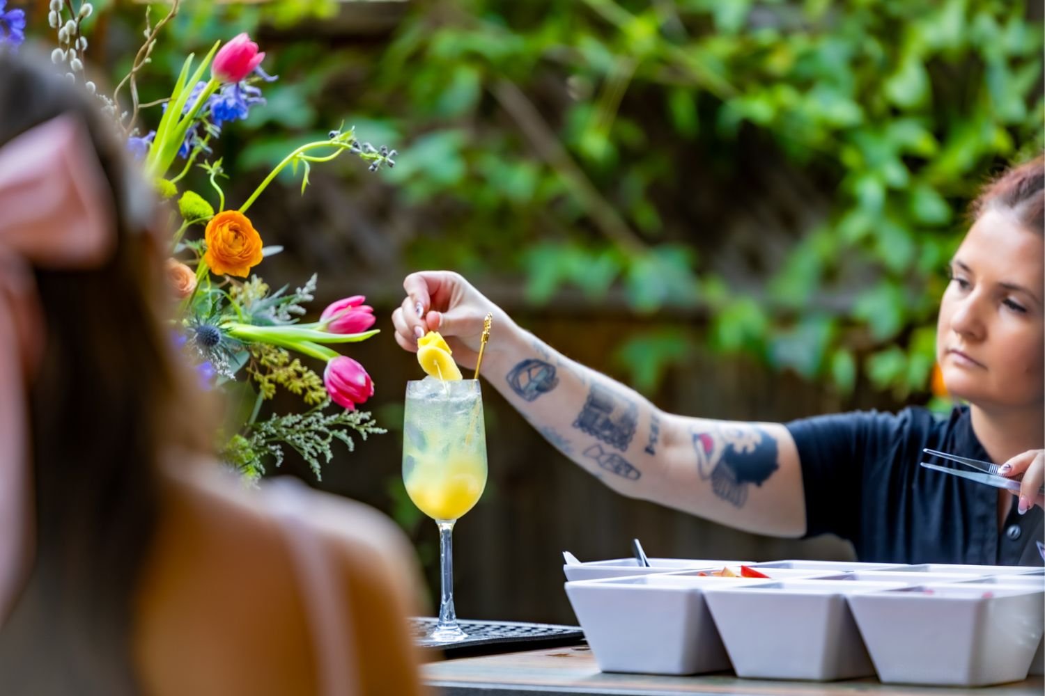A skilled bartender for hire artfully placing a fruit garnish into a flute as a guest looks on
