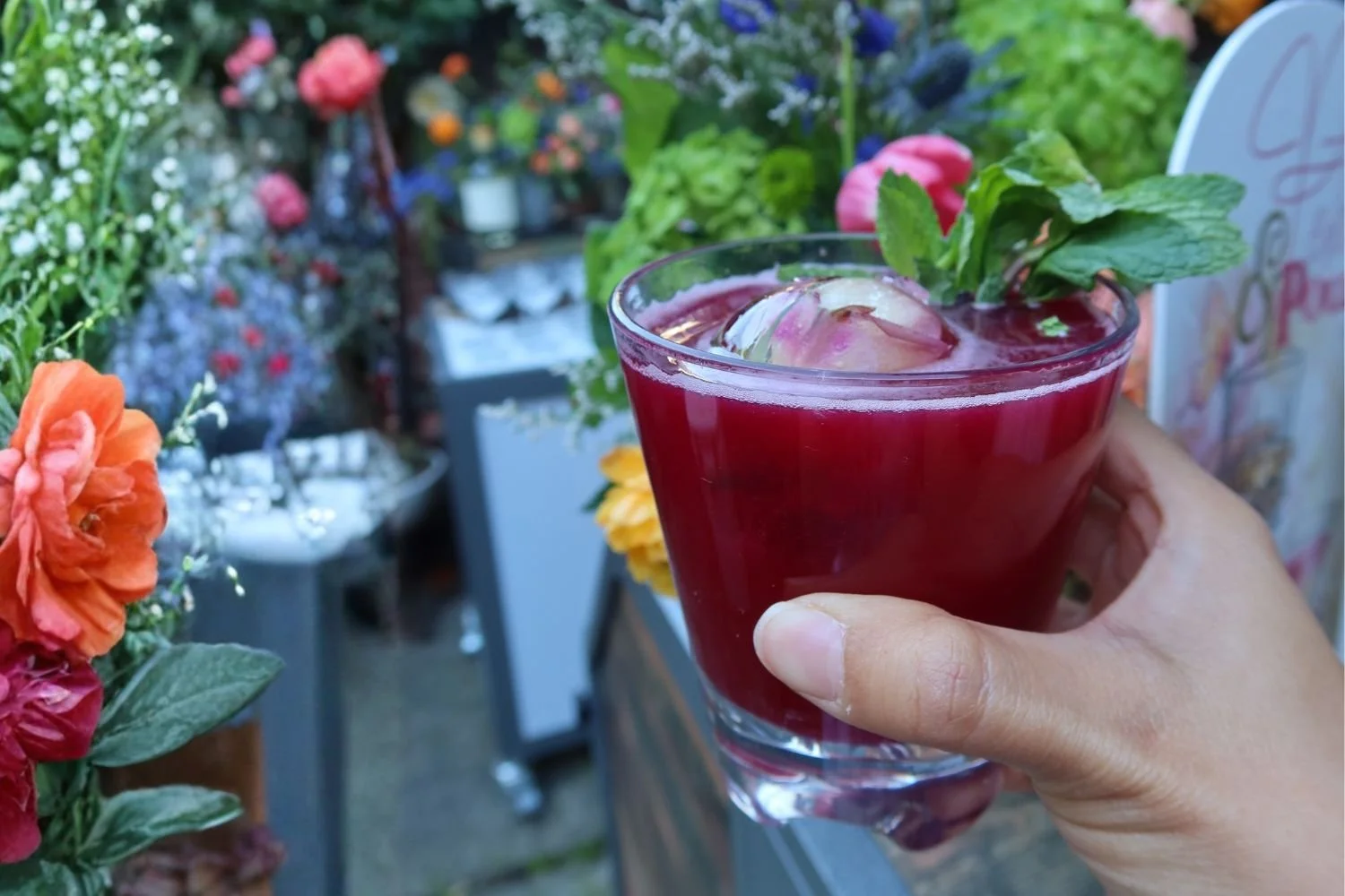 A deep red cocktail in the hand at a pop up event in the San Francisco bay area with a unique ice sphere