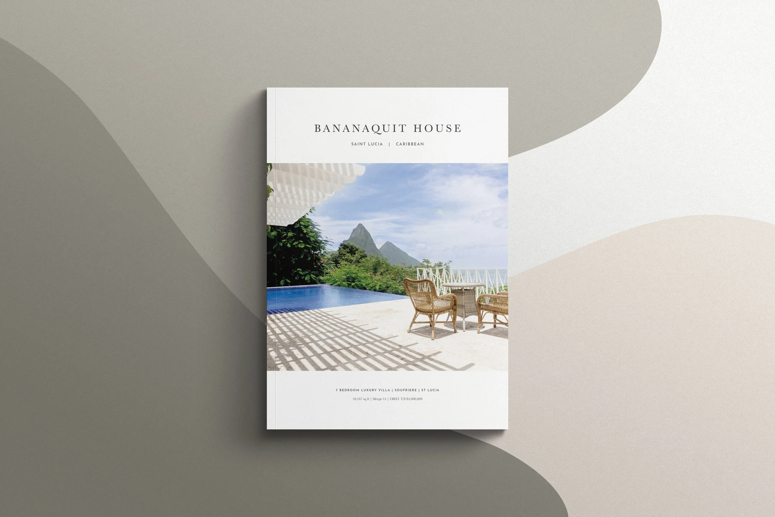 Brochure for Banaquit House featuring a balcony with wicker chairs, a table, a pool, lush greenery, and mountain scenery in Saint Lucia.