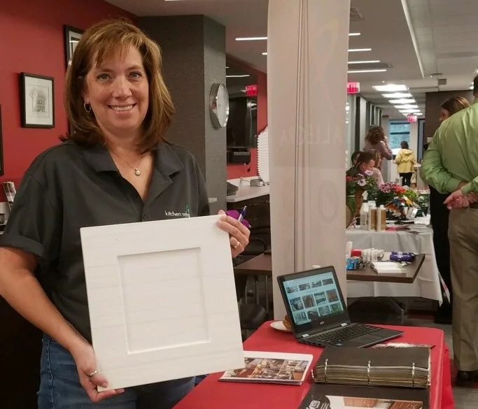 Shelly Carr, representing Kitchen Refresh, holds a sample door at the Edina Realty Vendor Fair.