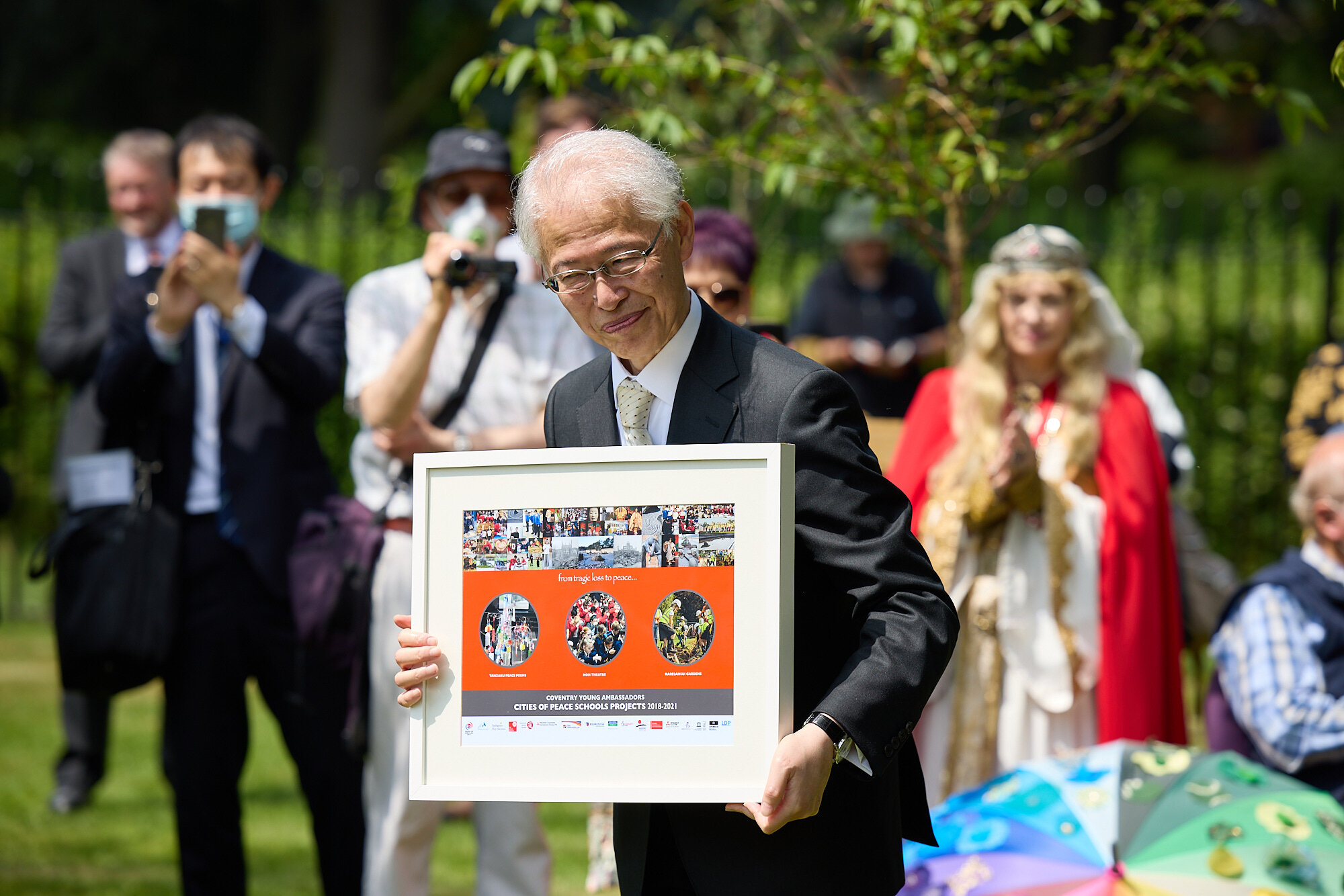 His Excellency Ambassador Hayashi is presented with a Cities of Peace Schools Projects Poster