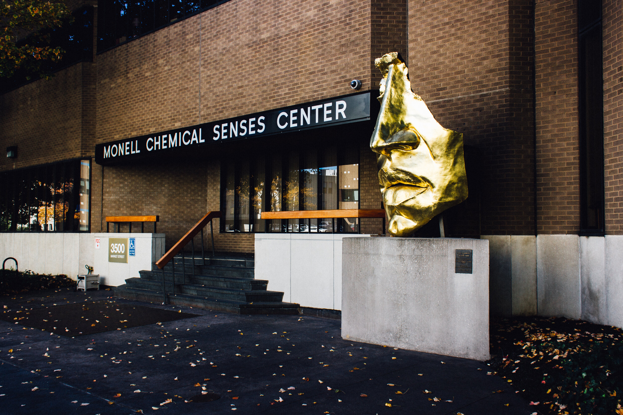  The front of the Monell Chemical Senses Center in Philadelphia, a brick building with a giant gold statue of a human nose. 