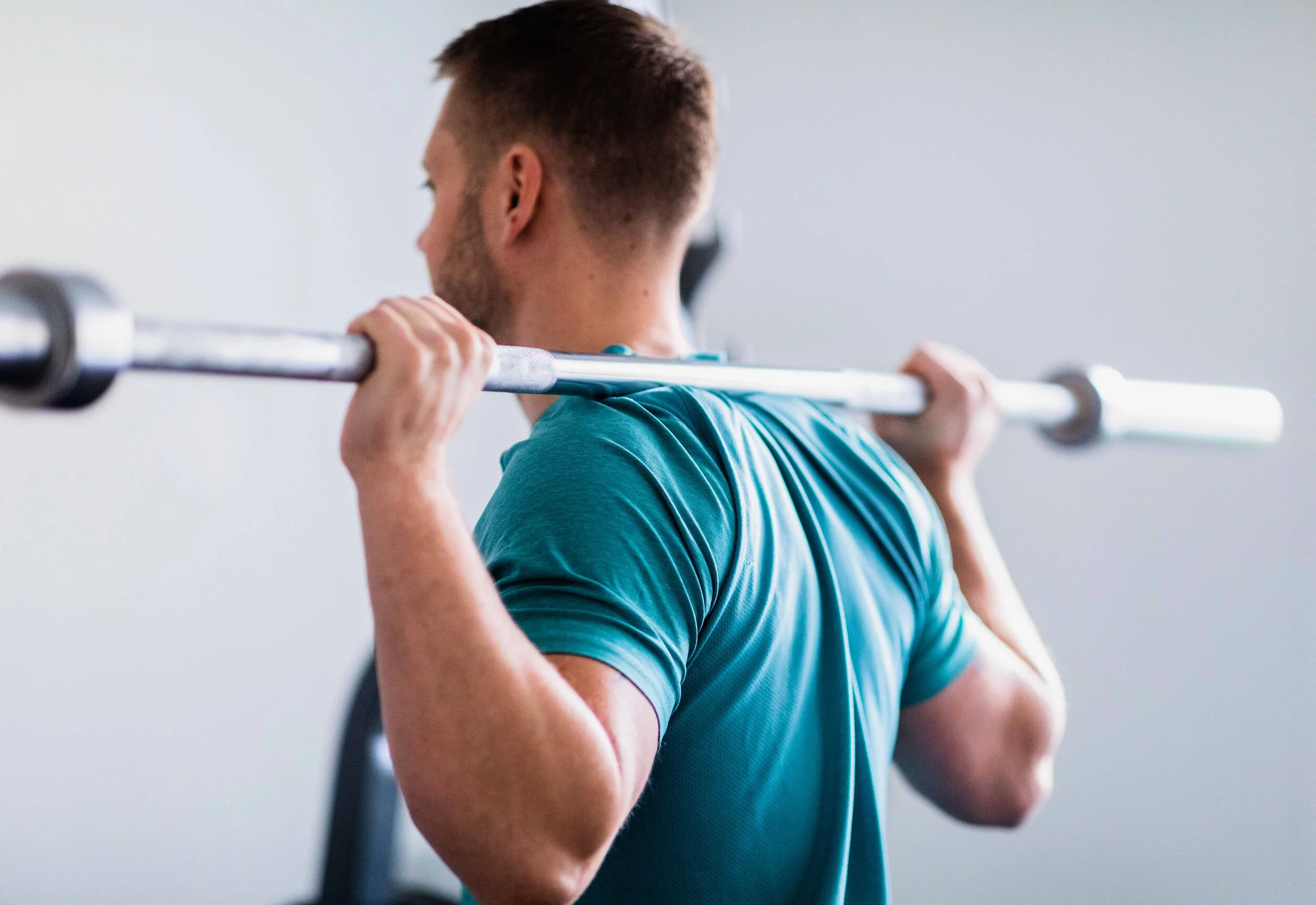 PT‑kund som tränar med skivstång i vår ljusa och välutrustade gymstudio. Fokus på teknik, styrka och trygg träning i en personlig miljö