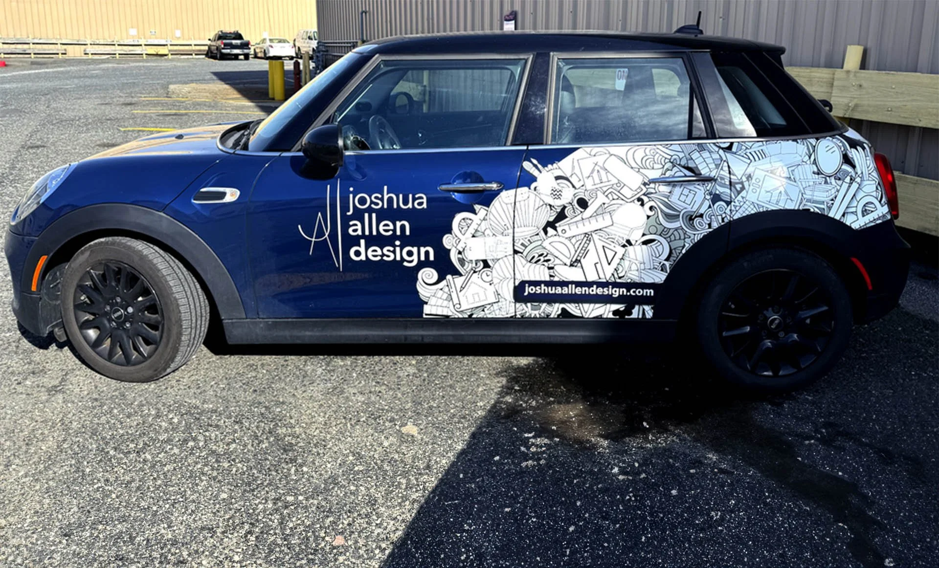 Blue Mini Cooper with Joshua Allen Design branding and artistic graphics on the side.