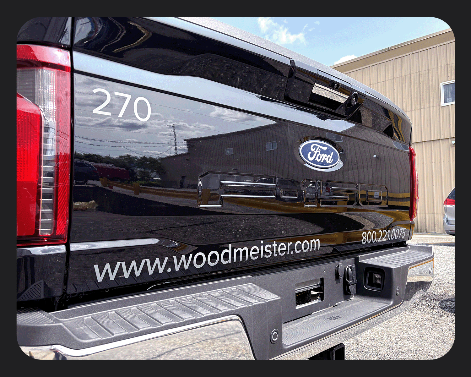 The back of a black Ford F-250 pickup truck with the number 270, a Ford logo, a website URL, and a phone number on the tailgate.