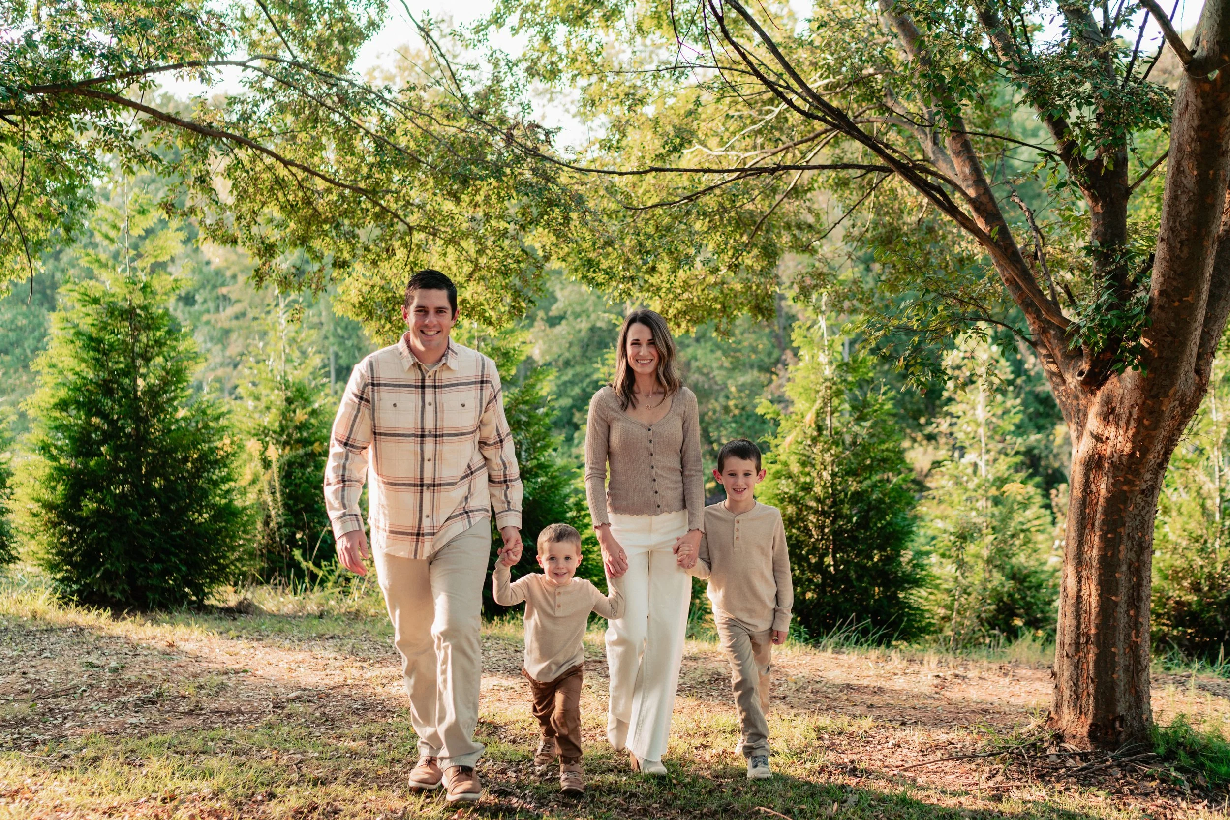 Family of seven walking hand in hand through a wooded park.