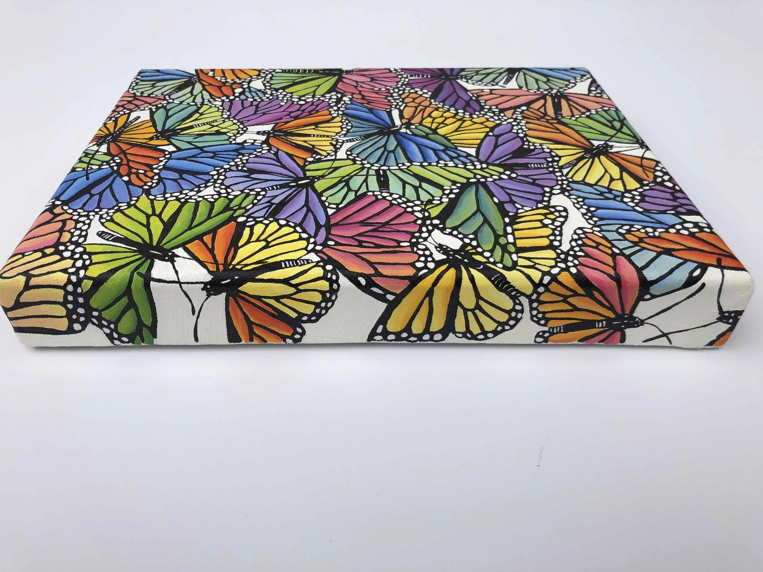 Photo of the original oil painting on canvas titled "Rainbow Scatter."  It features colorful monarch butterflies in flight during their migration.