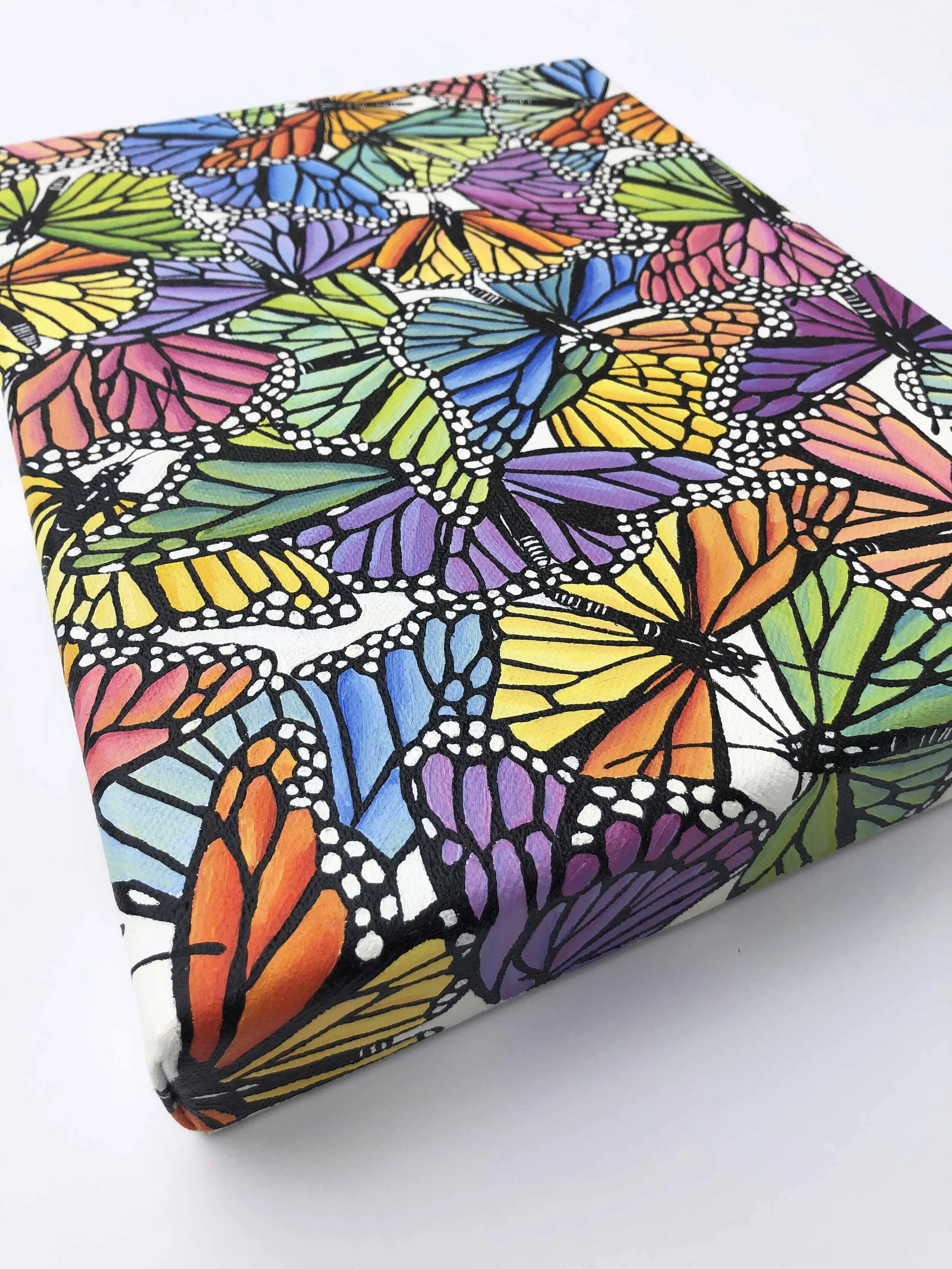 Photo of the original oil painting on canvas titled "Rainbow Scatter."  It features colorful monarch butterflies in flight during their migration.