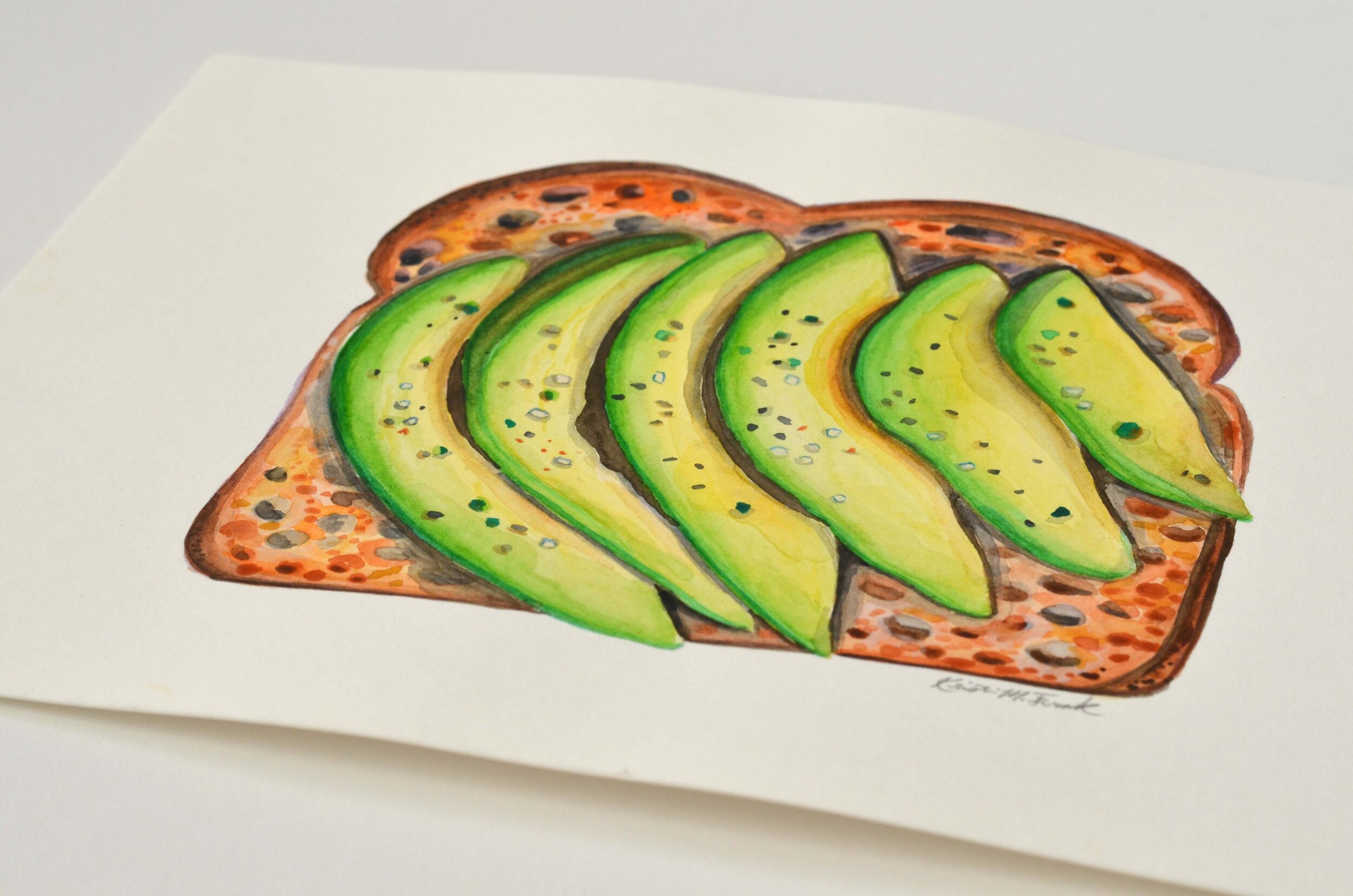 Watercolor of sliced avocado on toast. This painting is titled "Avocado Toast No.1" and it is by Kristin Frank.