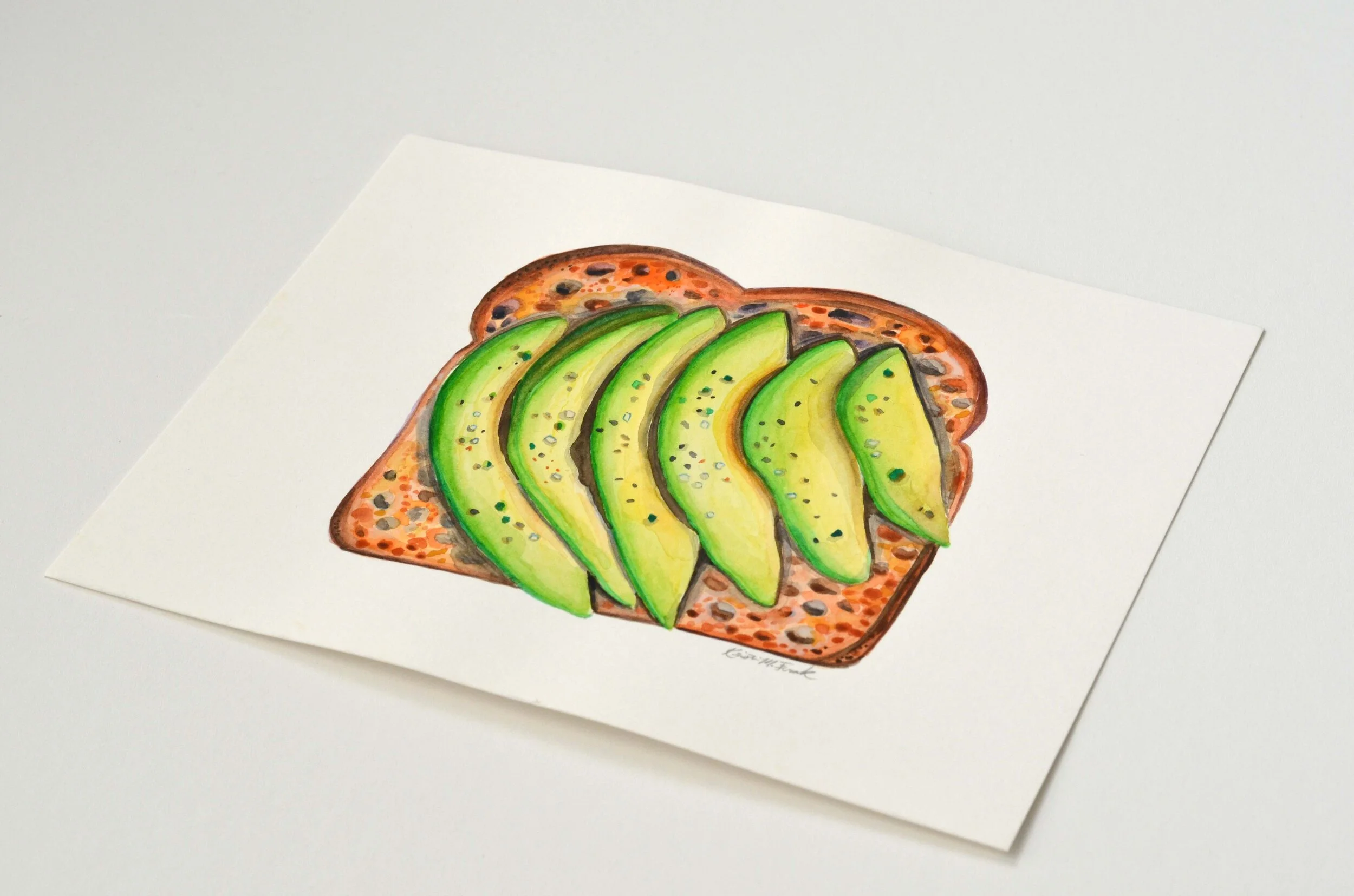 Watercolor of sliced avocado on toast. This painting is titled "Avocado Toast No.1" and it is by Kristin Frank.
