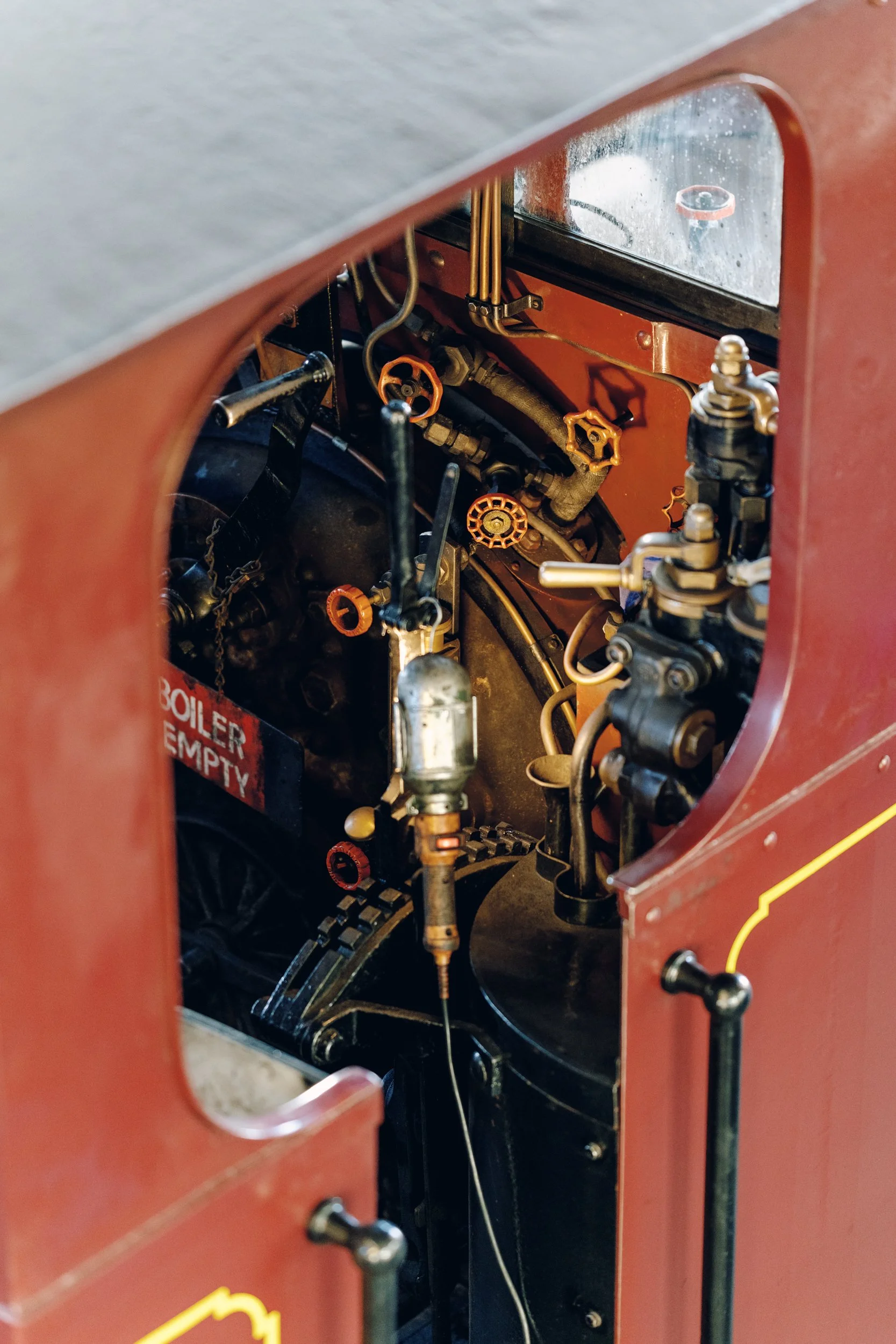 Inside view of an old industrial boiler with various pipes, valves, and gauges, and a sign saying 'Boiler Empty'.