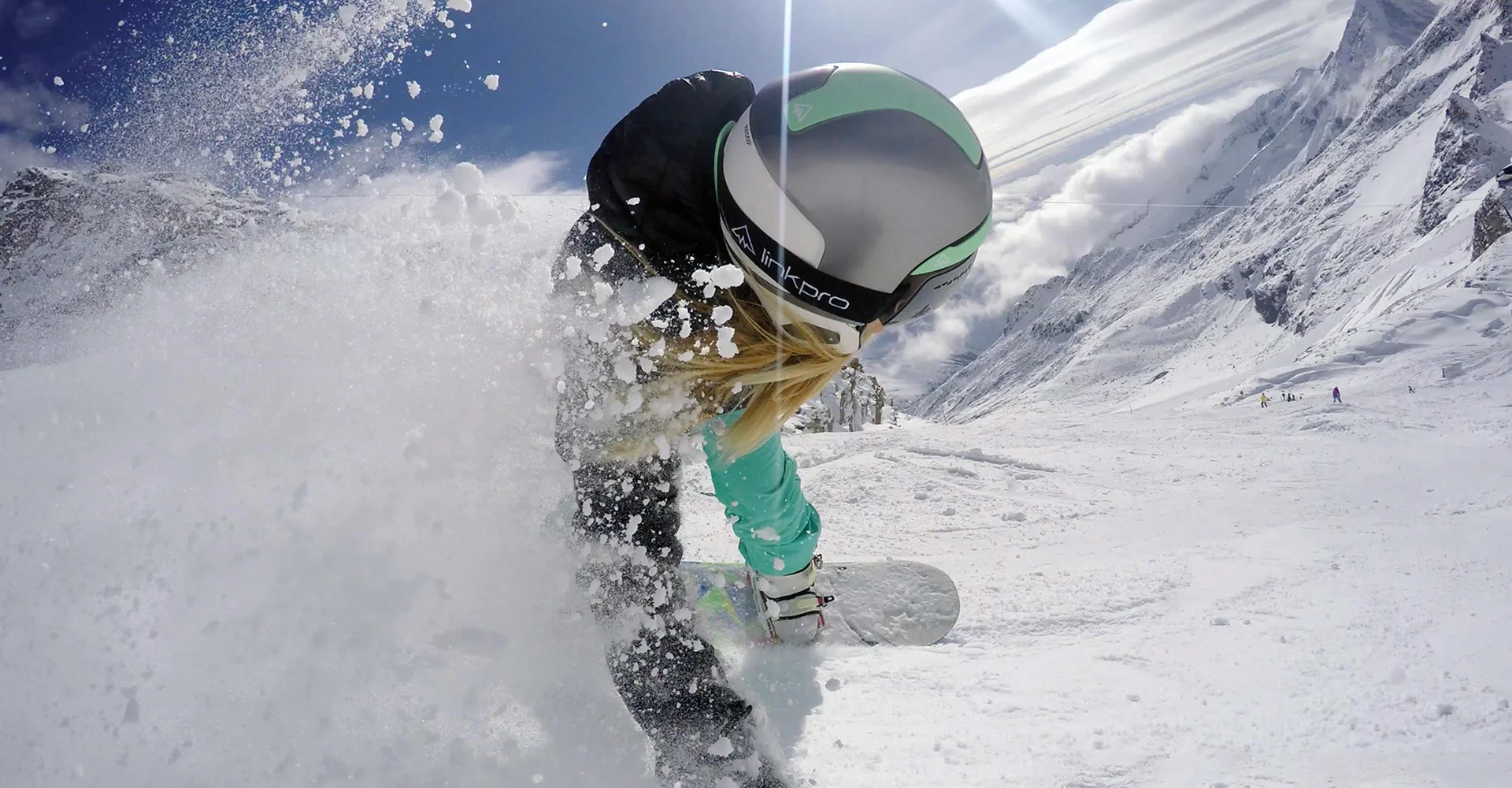 Link Pro - Curventa - In situ - snowboard - helmet - communication - headphones - silver helmet - action shot - female snowboarder - carving - mountain
