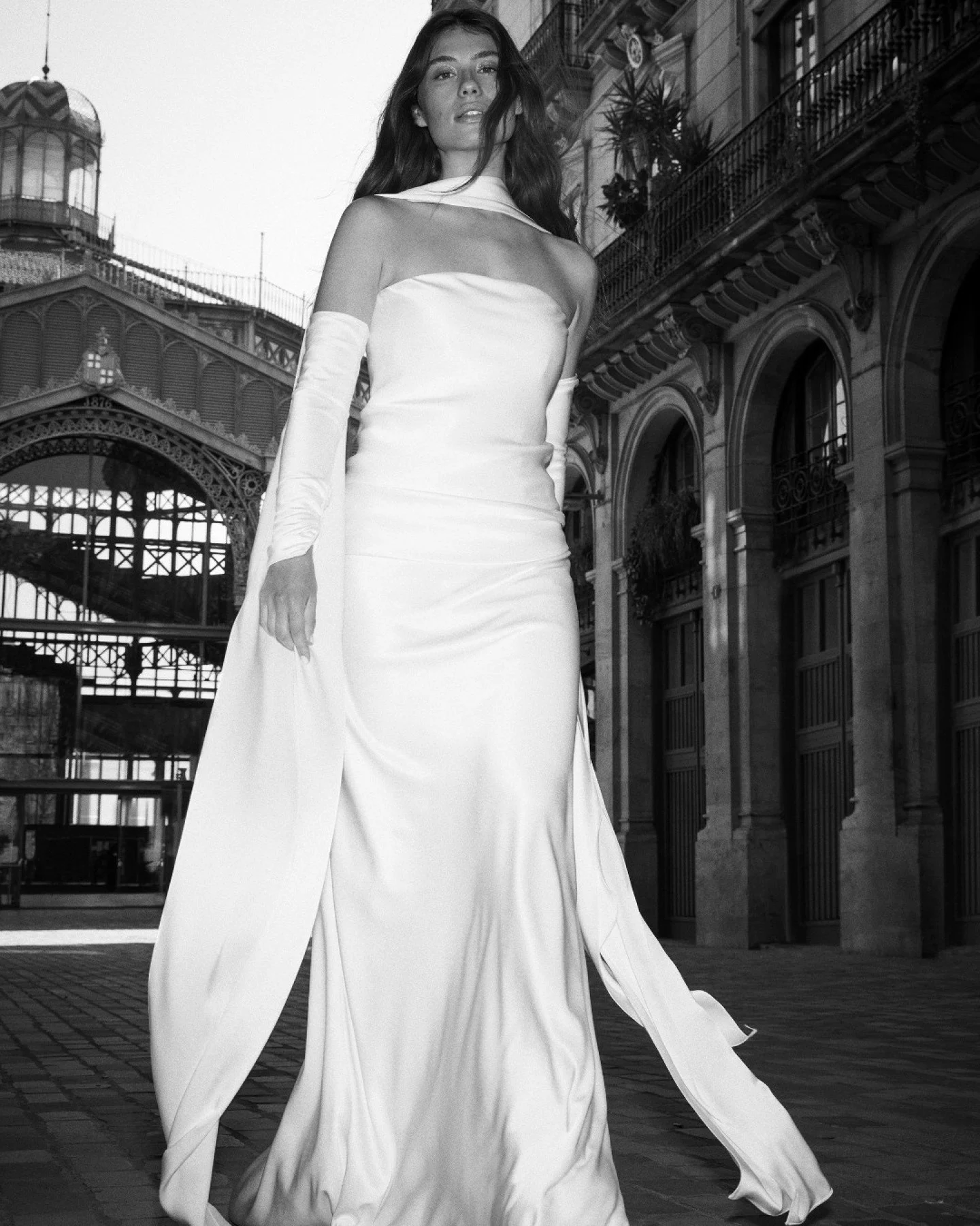 Meet Style 2615 by Jesus Peiro &mdash; a sumptuous Lucca Satin gown that drapes beautifully across the body, creating an elegant, sculpted silhouette. With removable sleeves and a matching neck scarf, this look delivers modern drama with timeless ref