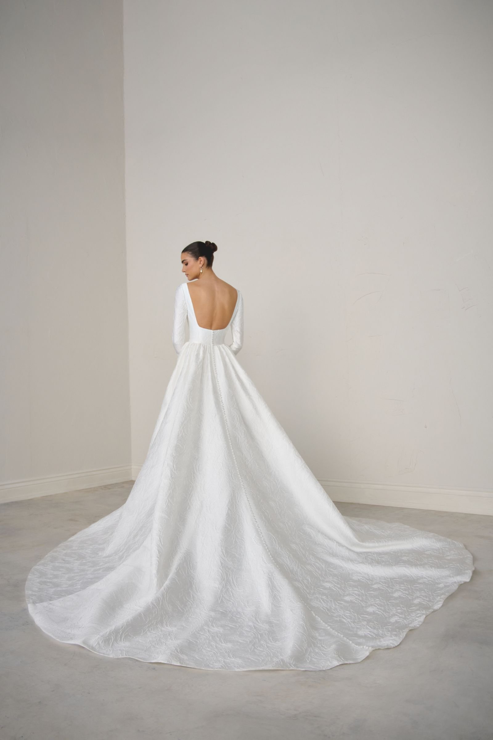 jJustin Alexander Signature Calista brocade A-line wedding dress with Sabrina neckline, long sleeves, princess seams, pockets and square back with chapel-length train.