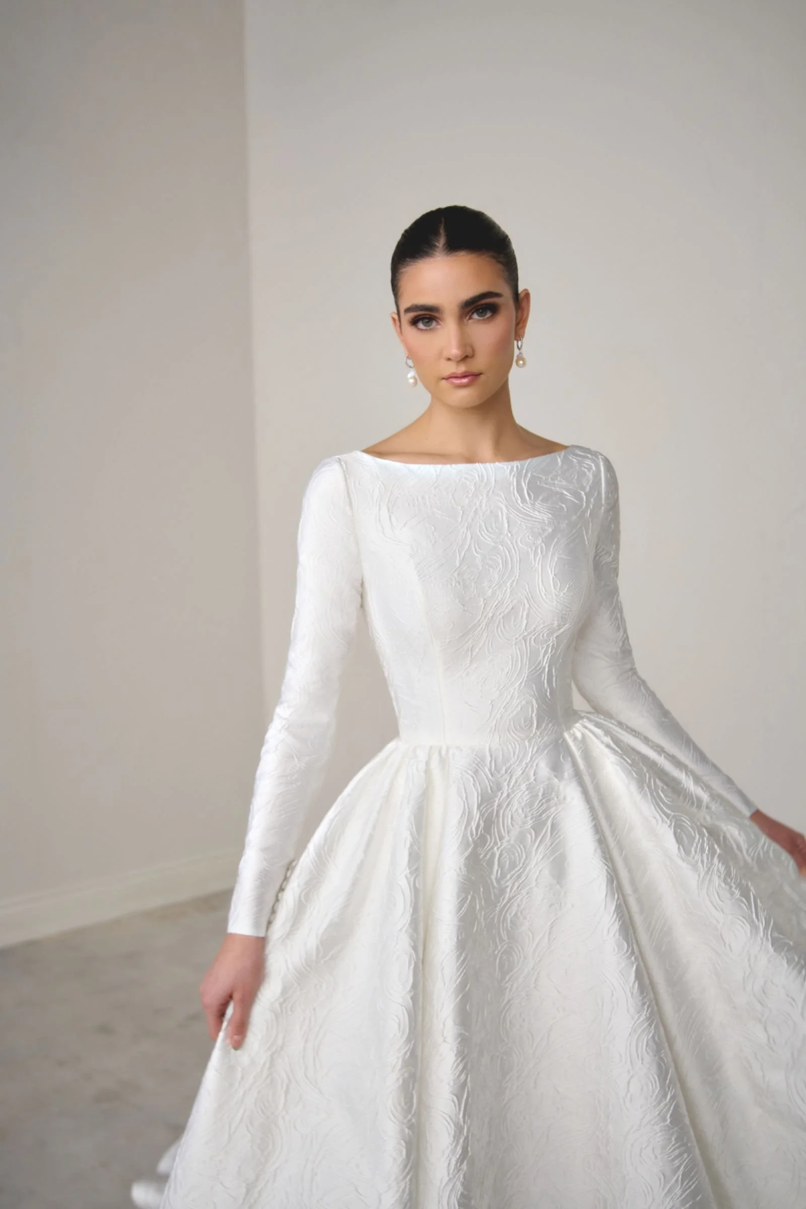 Justin Alexander Signature Calista brocade A-line wedding dress with Sabrina neckline, long sleeves, princess seams, pockets and square back with chapel-length train.