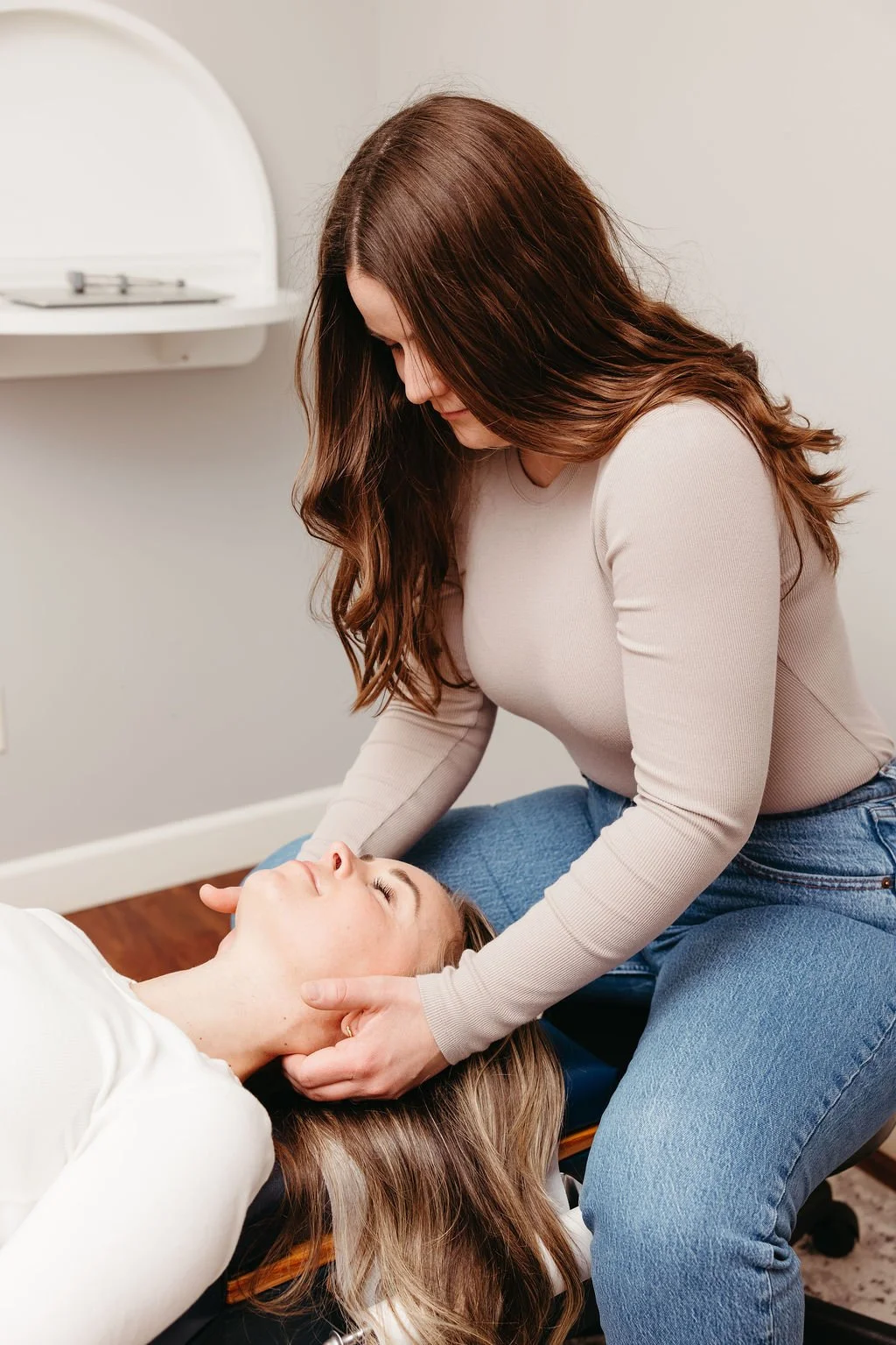Women adjusting a female patient for neck pain, headaches, TMJ and more.